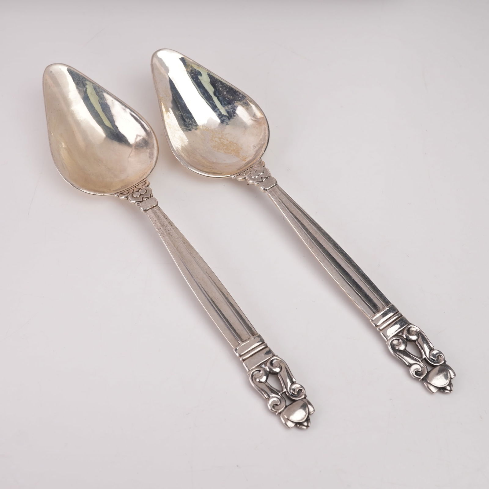 2pc Georg Jensen Sterling Silver Teaspoons, Acorn: A two-piece lot of Georg Jensen sterling silver teaspoons in the Acorn pattern, designed by Johan Rohde in 1915. Each marked Georg Jensen Sterling Denmark. The pattern features a fluted handle with sc