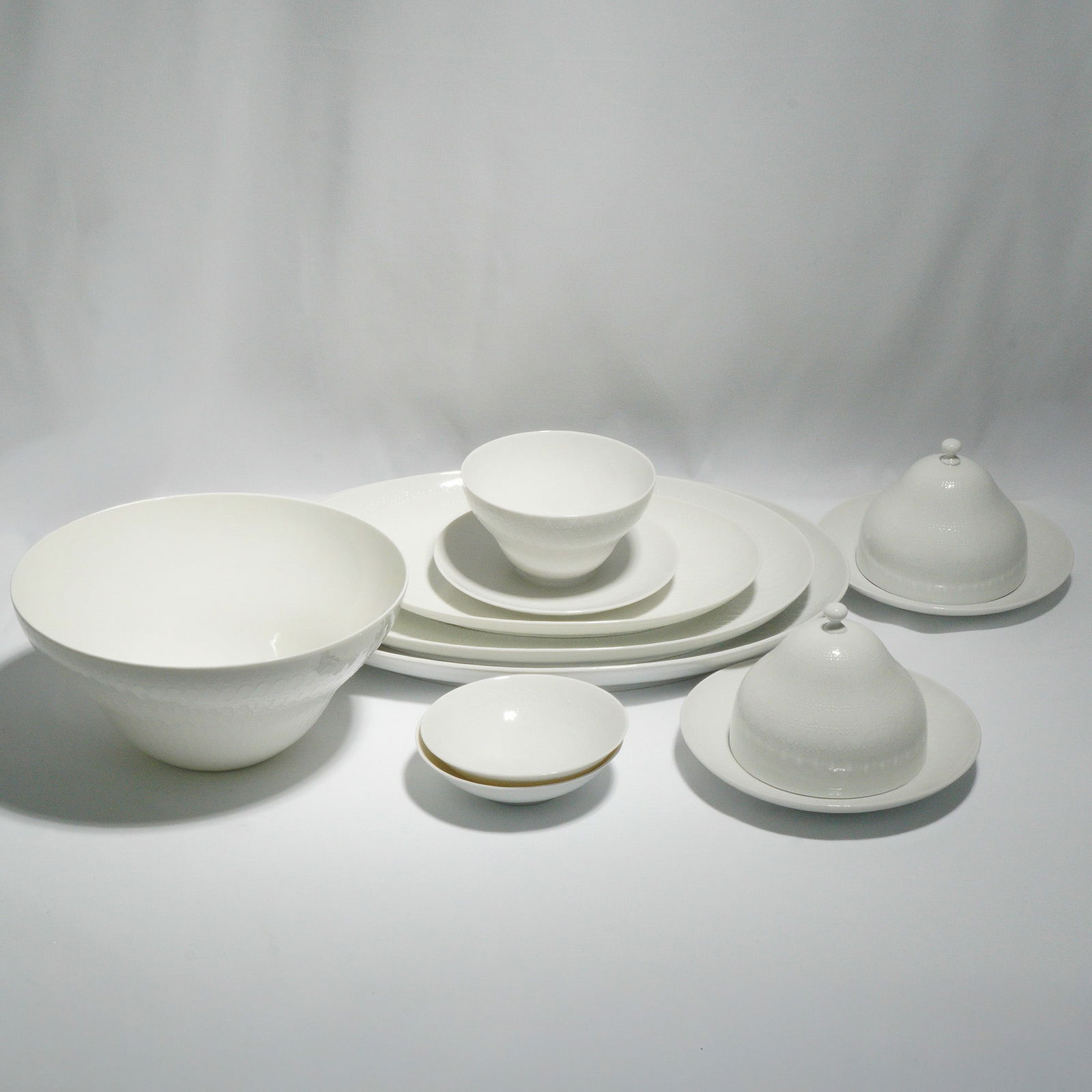 11pc Rosenthal by Bjorn Wiinblad Serving Bowls & Platters, White Romance: Porcelain serving set from the White Romance line, designed by celebrated Danish artist Bjorn Wiinblad. This collection features crisp white porcelain with Wiinblad's signature embossed lace-like patt