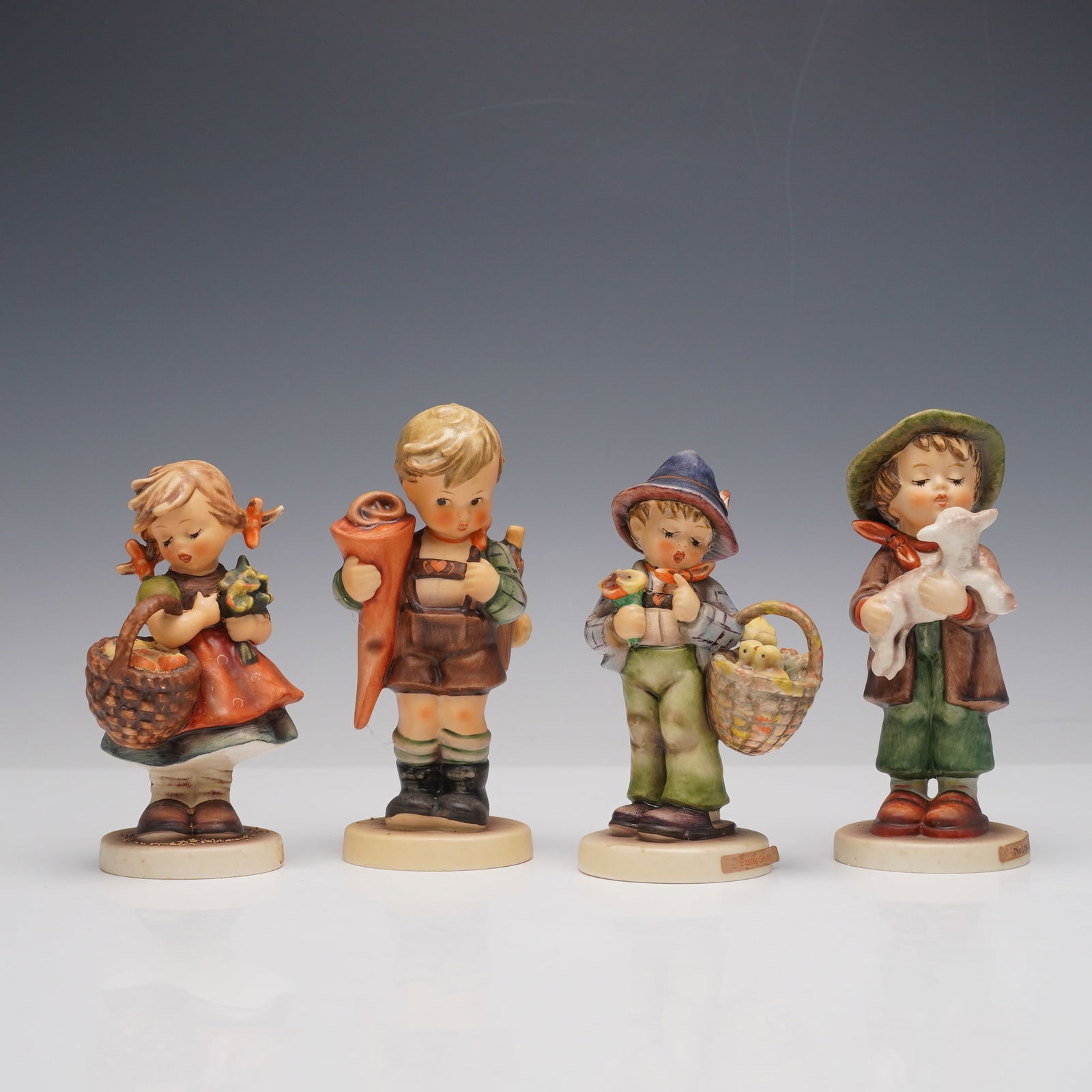 4pc Goebel Hummel Figurines: This sweet set captures classic pastoral charm in Hummel form. The Lost Sheep shows a boy gently cradling a baby lamb in his arms. Easter Greetings features a boy holding flowers and a basket filled w