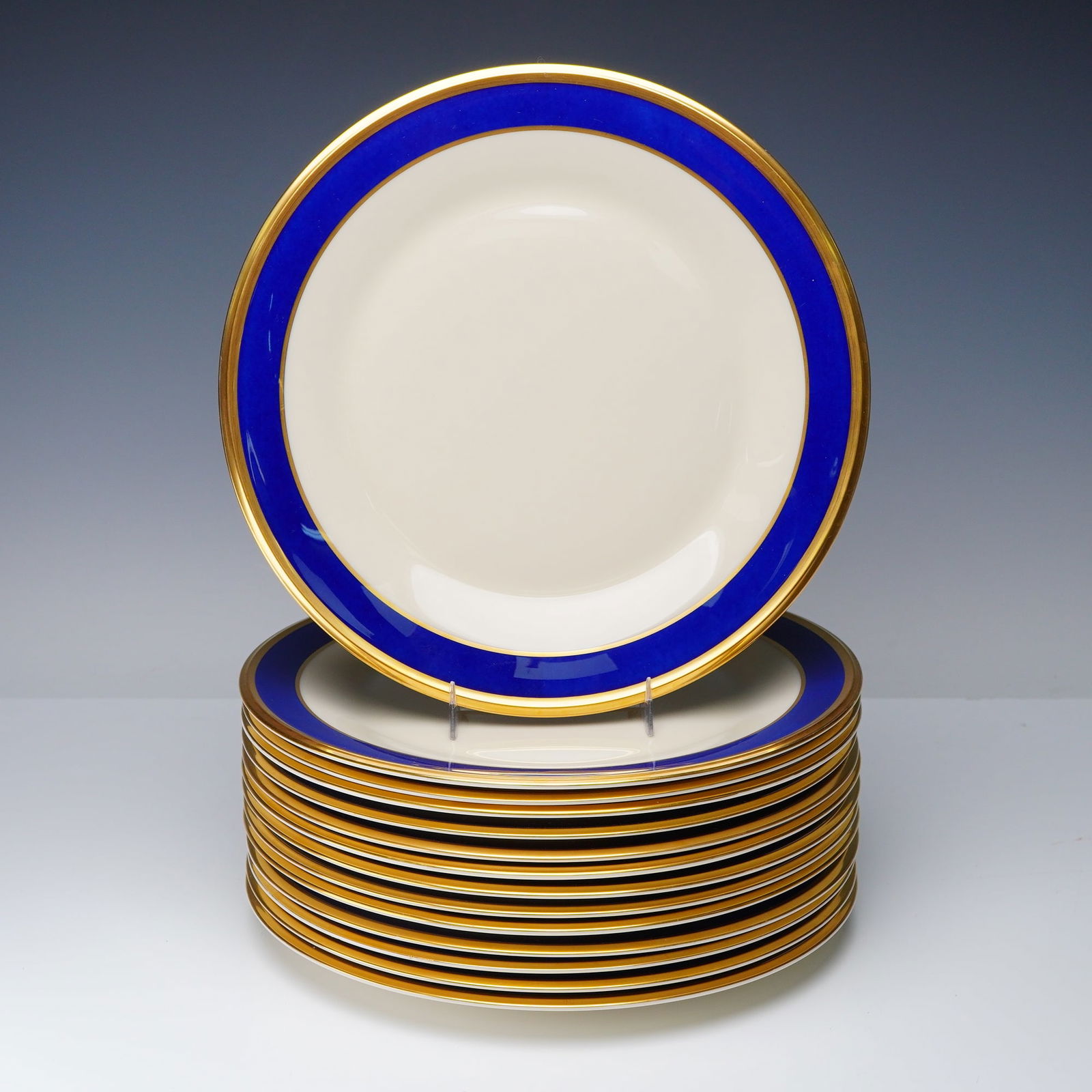 14pc Lenox Blue Band and Gold Rim Dinner Plates: A group of fourteen Lenox dinner plates featuring a deep cobalt blue band bordered by gold trim on a cream ground. Each plate is marked "Lenox Made in U.S.A. Special" on the underside. Pattern L169. D