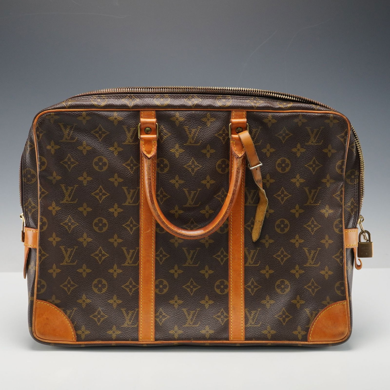 Louis Vuitton Monogram Porte-Documents Voyage Briefcase: A classic Louis Vuitton Porte-Documents Voyage briefcase crafted in the signature Monogram coated canvas with natural Vachetta leather trim and gold-tone brass hardware. Designed with dual rolled leat