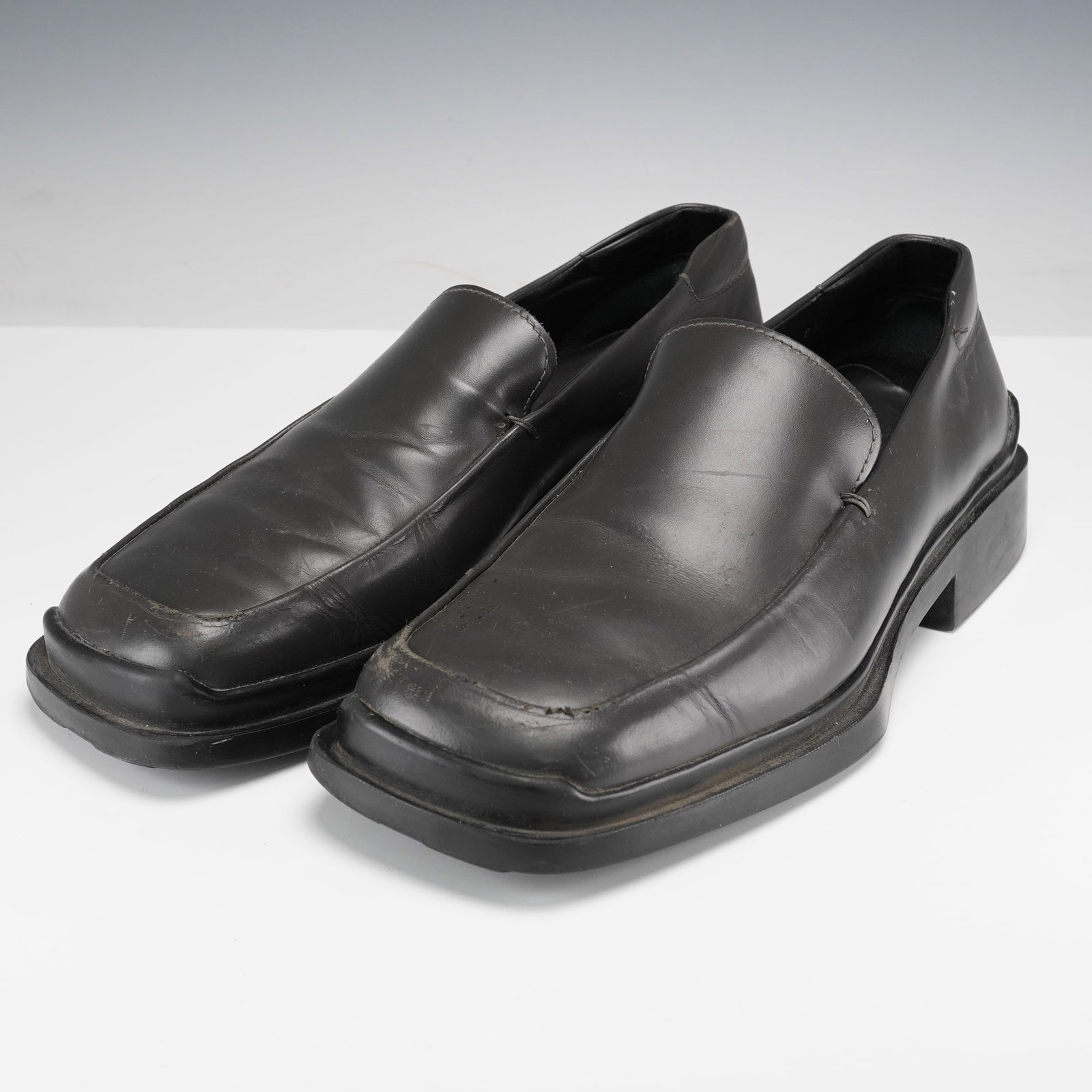 Prada Men's Black Leather Loafers: Made in Italy, these Prada black leather loafers feature a sleek square toe and chunky rubber sole, embodying the brand's refined yet modern aesthetic. The interior is stamped with the Prada logo and