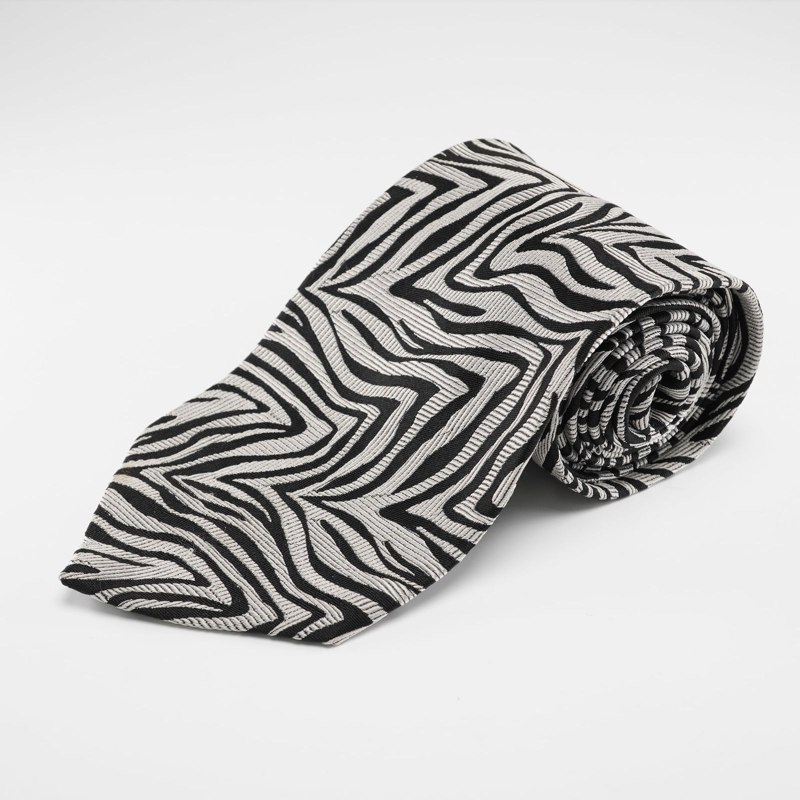 Gianni Versace Silk Necktie Zebra Pattern: Gianni Versace pure silk necktie featuring a black and silver zebra inspired pattern with a finely textured woven surface and crisp linear detailing, finished with the Gianni Versace name on the back.