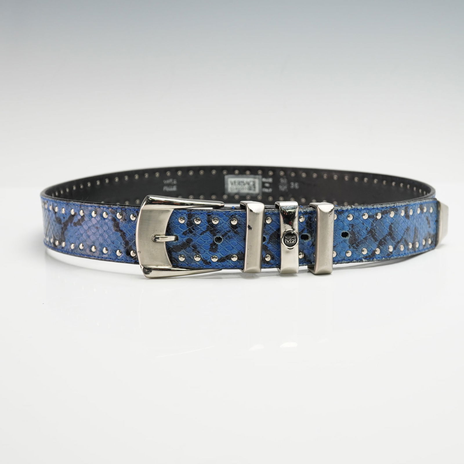 Versace V2 Classic Snakeskin Leather Belt: Blue snakeskin-patterned leather with metal stud detailing, fitted with a polished silver-tone buckle and triple keepers displaying the V2 logo stamp, marked "Vera Pelle" and "Made in Italy". Issued:
