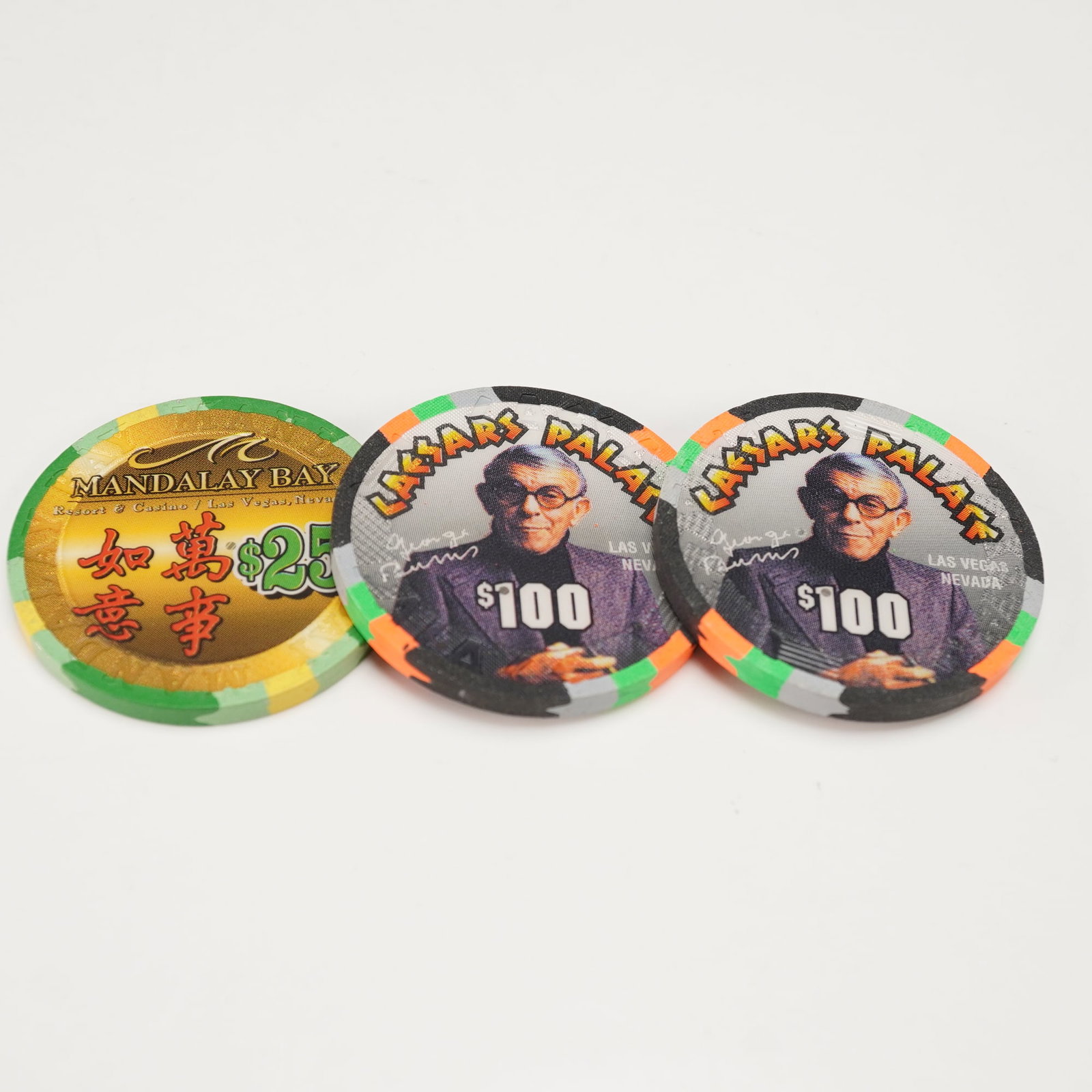 3pc Mandalay Bay and Caesars Palace Casino Chips: Group of three collectible casino chips from Las Vegas resorts, including one $25 chip from Mandalay Bay featuring a stylized 2000 dragon motif and two $100 chips from Caesars Palace commemorating the