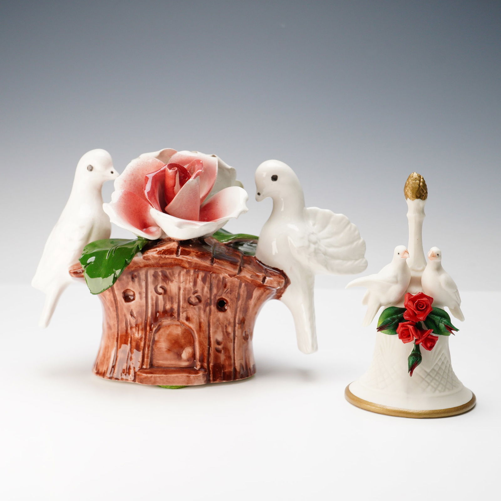 2pc Capodimonte Decorative Floral Dove Bell & Figurine: The first piece is a delicate porcelain bell adorned with two white doves perched above vibrant red roses and green leaves, highlighted with gilt trim along the base and finial, bearing the blue "Crow