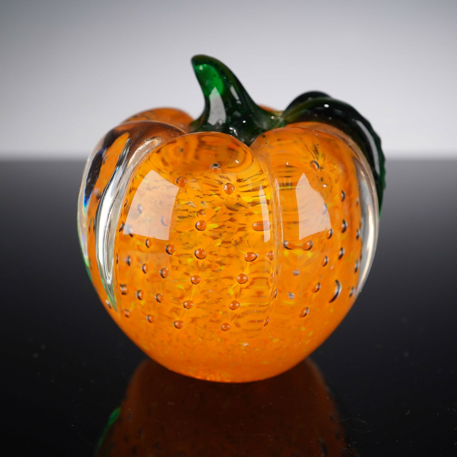 Lenox Art Glass Pumpkin Paperweight: This vibrant Lenox glass pumpkin paperweight features a rich orange body infused with controlled bubbles and internal color, accented by a clear sculpted form and a vivid green applied leaf and stem.