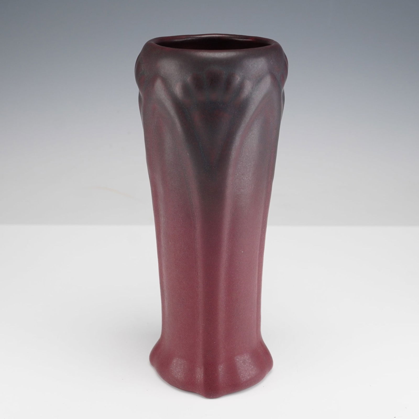 Van Briggle Pottery Floral Mulberry Vase: Van Briggle Pottery bud vase in a mulberry glaze, featuring an elongated tapered form with stylized Art Nouveau leaf and fan motifs around the rim, finished in a matte two tone gradient that deepens t