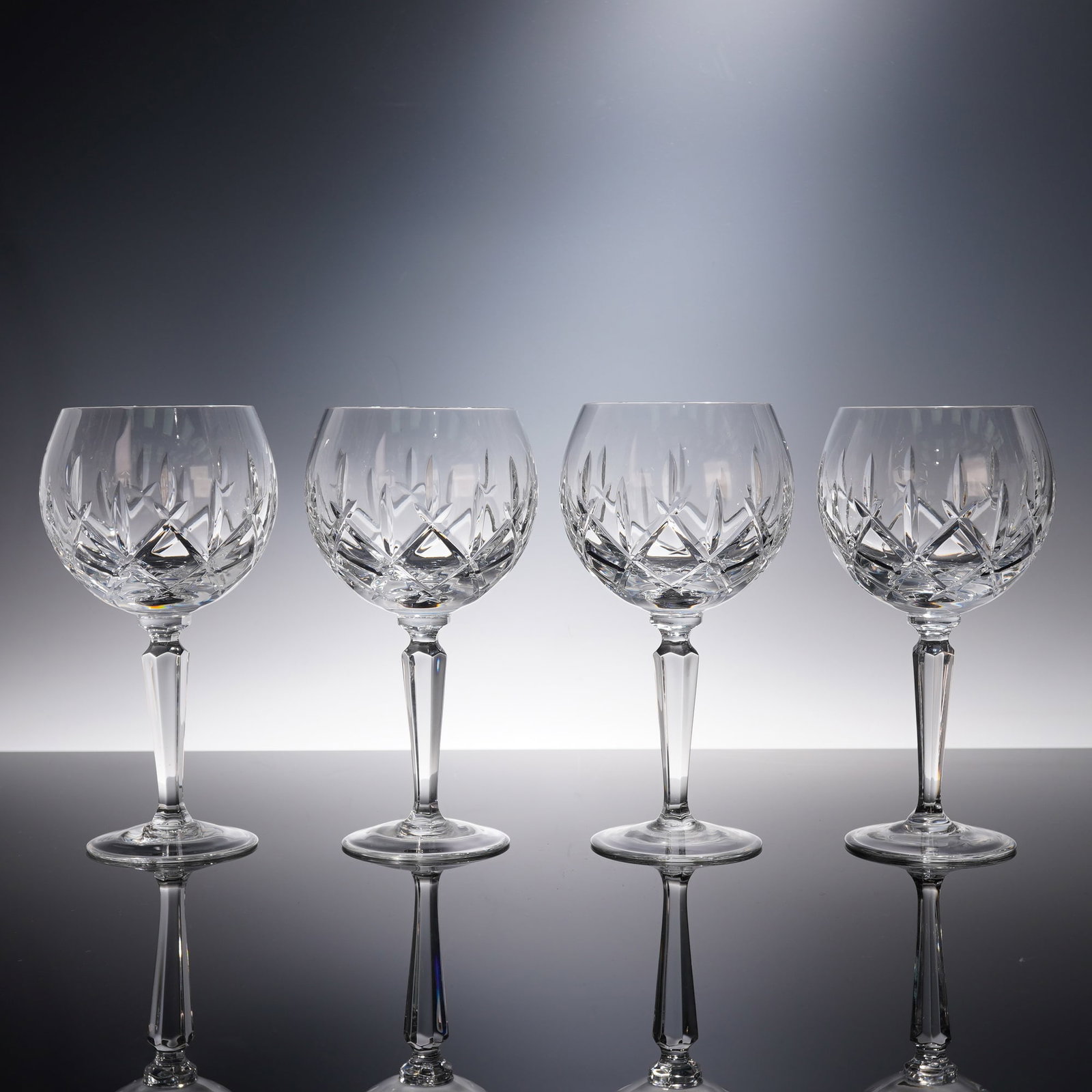 4pc Crosshatched Cut Crystal Balloon Wine Glasses: A set of four balloon wine glasses crafted in clear cut crystal with bold crosshatched and starburst patterns that reflect the light beautifully. Each glass features a faceted stem that adds balance a