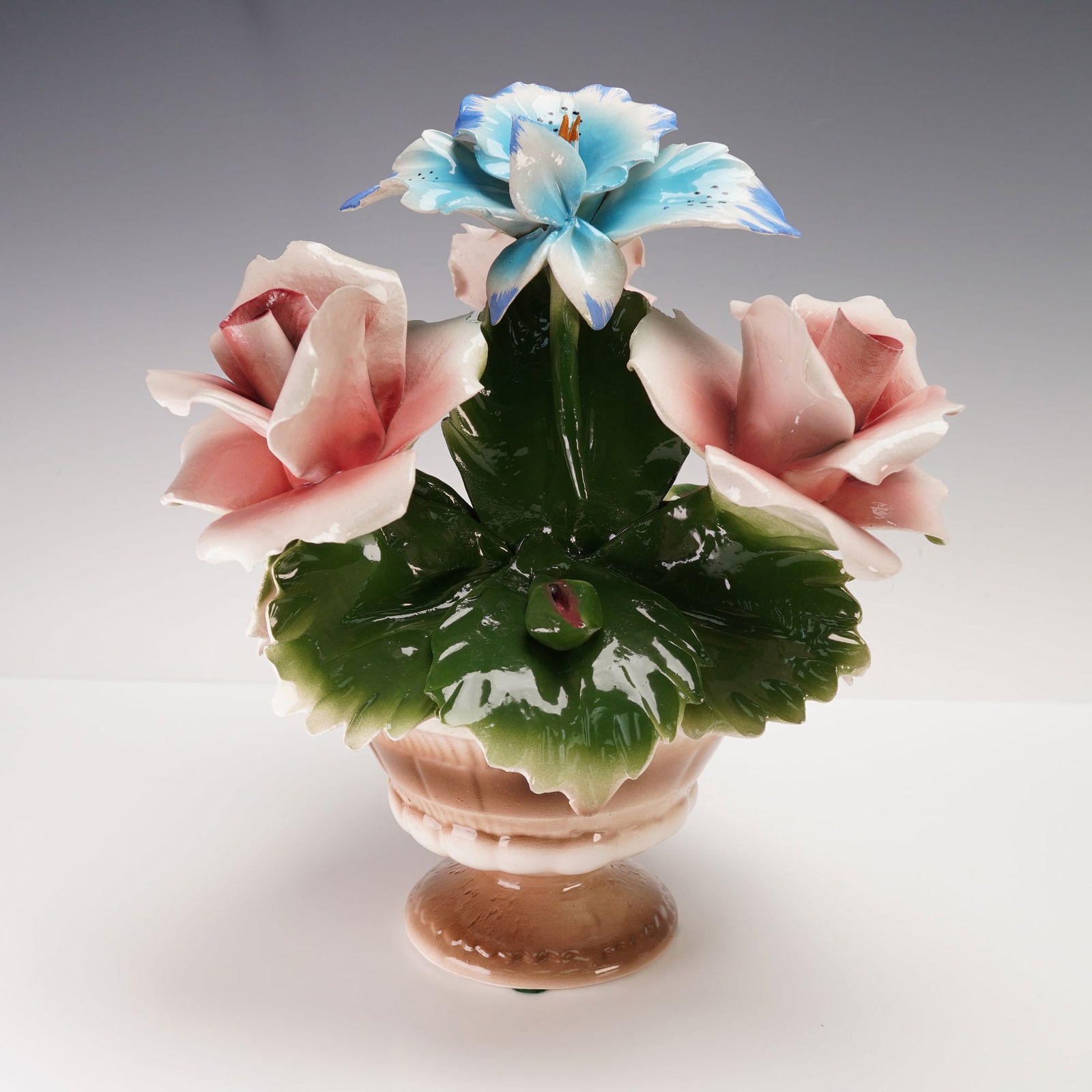 Nuova Capodimonte Italian Porcelain Rose Floral Basket Centerpiece: A beautiful Nuova Capodimonte Italian porcelain floral arrangement in a pedestal basket form, featuring finely hand-modeled and hand-painted flowers. The piece displays a striking composition of large