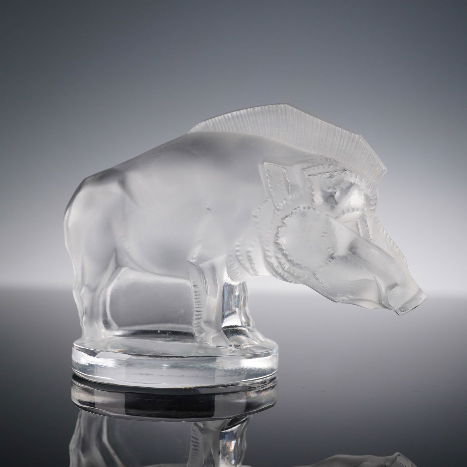 Lalique Crystal Paperweight, Sanglier Boar Mascot: This clear and frosted Lalique crystal paperweight depicts a stylized boar, originally designed as a 1920s hood ornament and modeled with bold Art Deco lines, a textured mane, and a satin finished bod