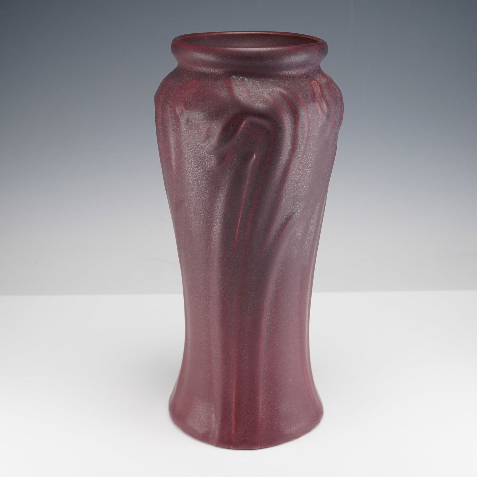 Van Briggle Pottery Mulberry Vase, Daffodil: This tall Van Briggle pottery vase is finished in a rich mulberry glaze and features a flowing daffodil motif in raised relief, the organic Art Nouveau lines wrapping gracefully around the body and ri