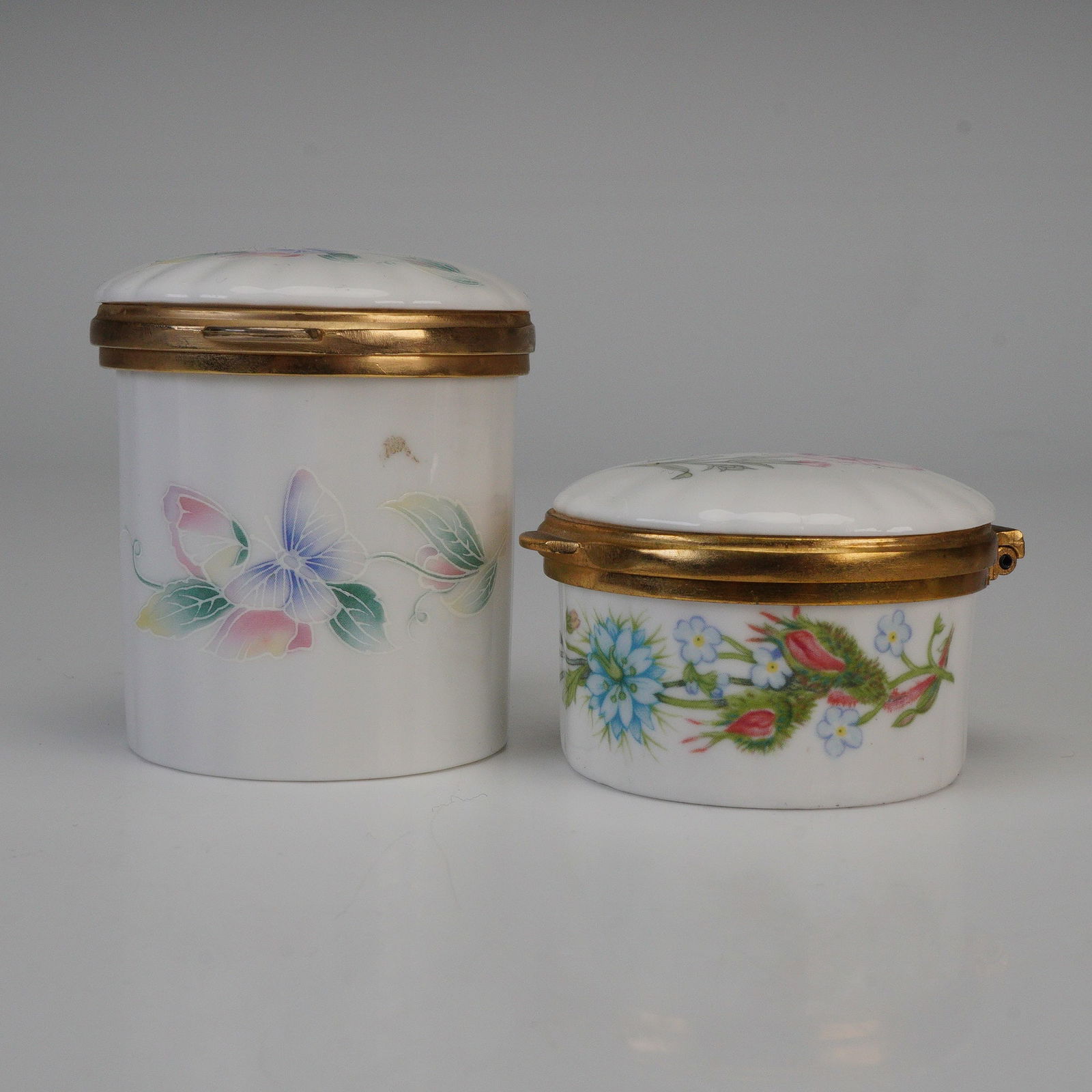 2pc Aynsley Bone China Lidded Boxes, Little Sweetheart & Wild Tudor: Two fine English bone china lidded boxes by Aynsley, featuring the Little Sweetheart and Wild Tudor patterns. Each piece is decorated with delicate floral motifs and fitted with gilt metal rims and hi