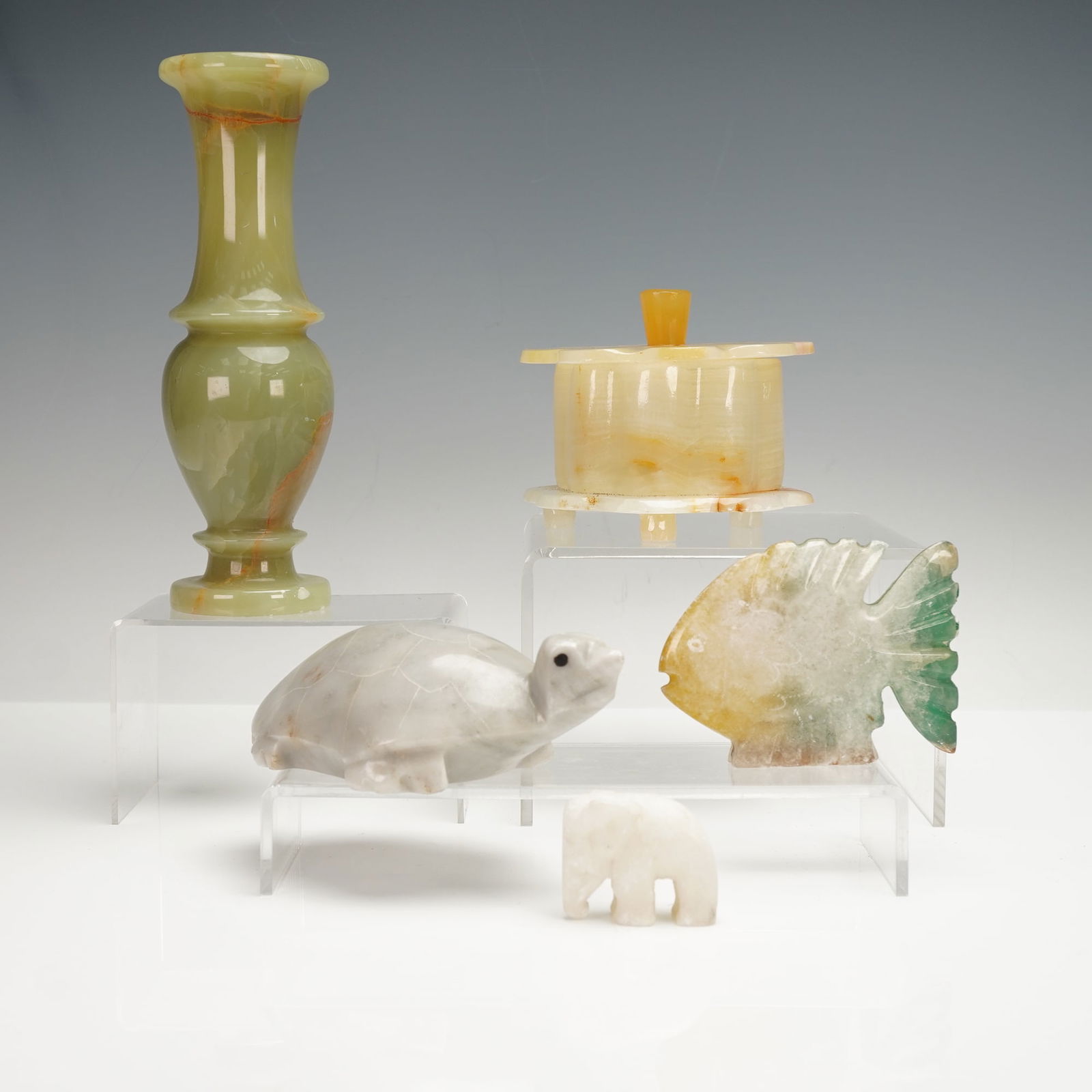 5pc Carved Stone Vanity Box, Bud Vase and Paperweights Figurines: A five-piece assortment of carved stone objects including a lidded vanity treasure box in warm cream onyx, a green onyx bud vase with natural veining, a carved fish paperweight with green and amber to