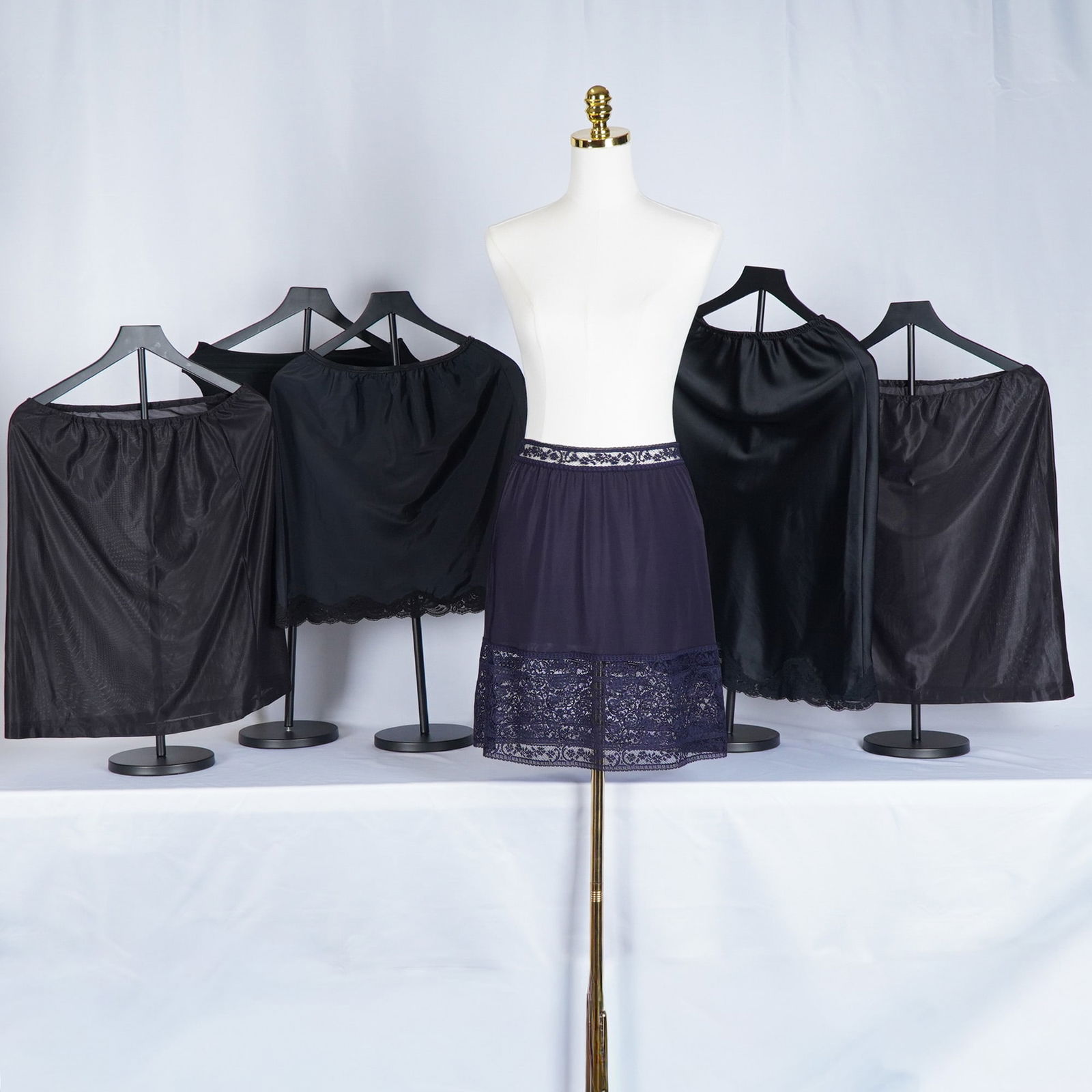 6pc Black and Navy Satin Lingerie Slips: The lot features various lengths and styles, including lace-trimmed hems, silky full slips, and a navy lace-panel half slip. Makers include Donna Karan Intimates and Spanx, with assorted unbranded pie