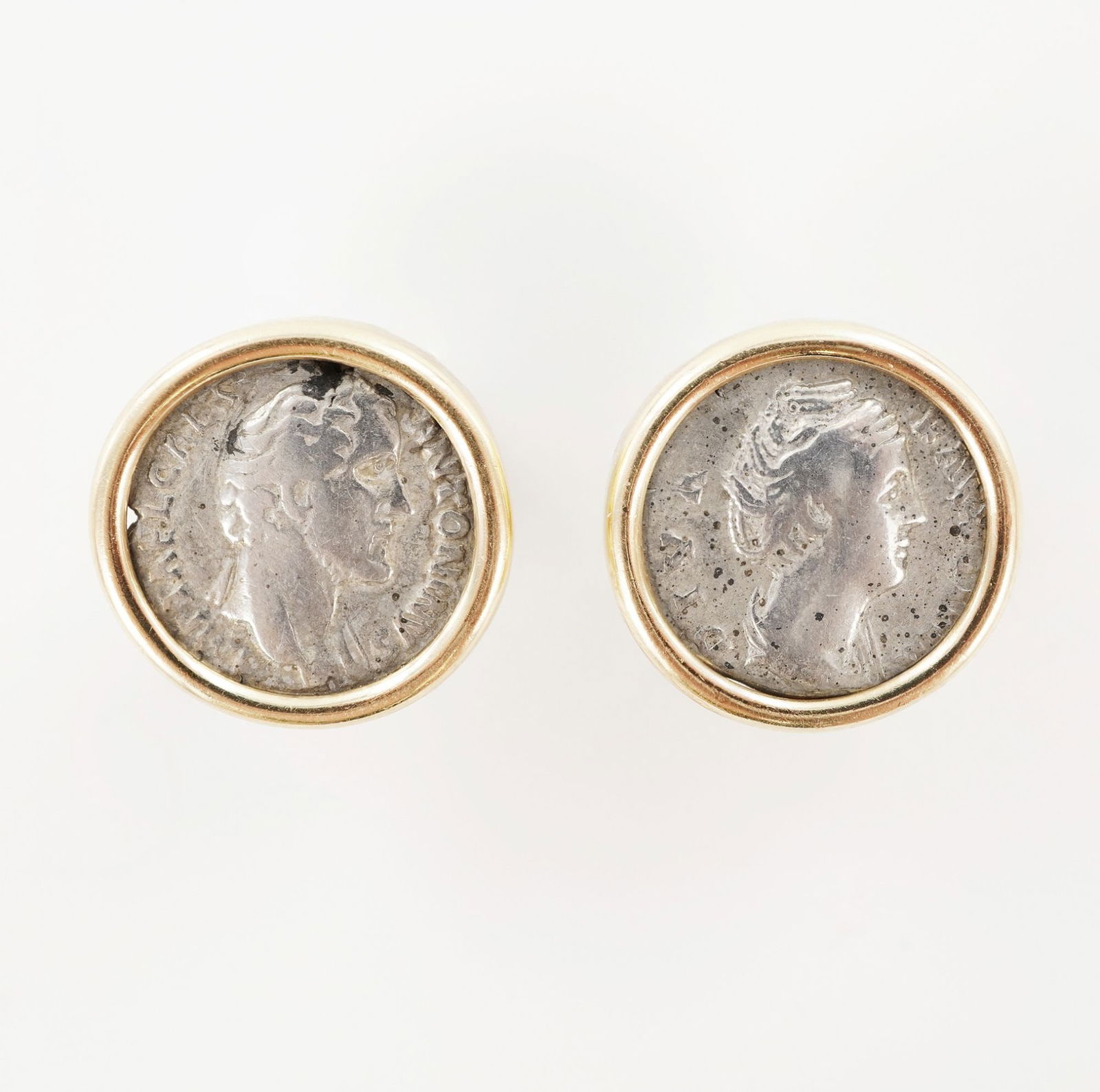 14K Gold Ancient Roman Coin Earrings: Each earring centers an ancient Roman coin depicting a male portrait on the obverse and a standing female figure on the reverse. The inscriptions include ANTONINI and other Latin lettering consistent