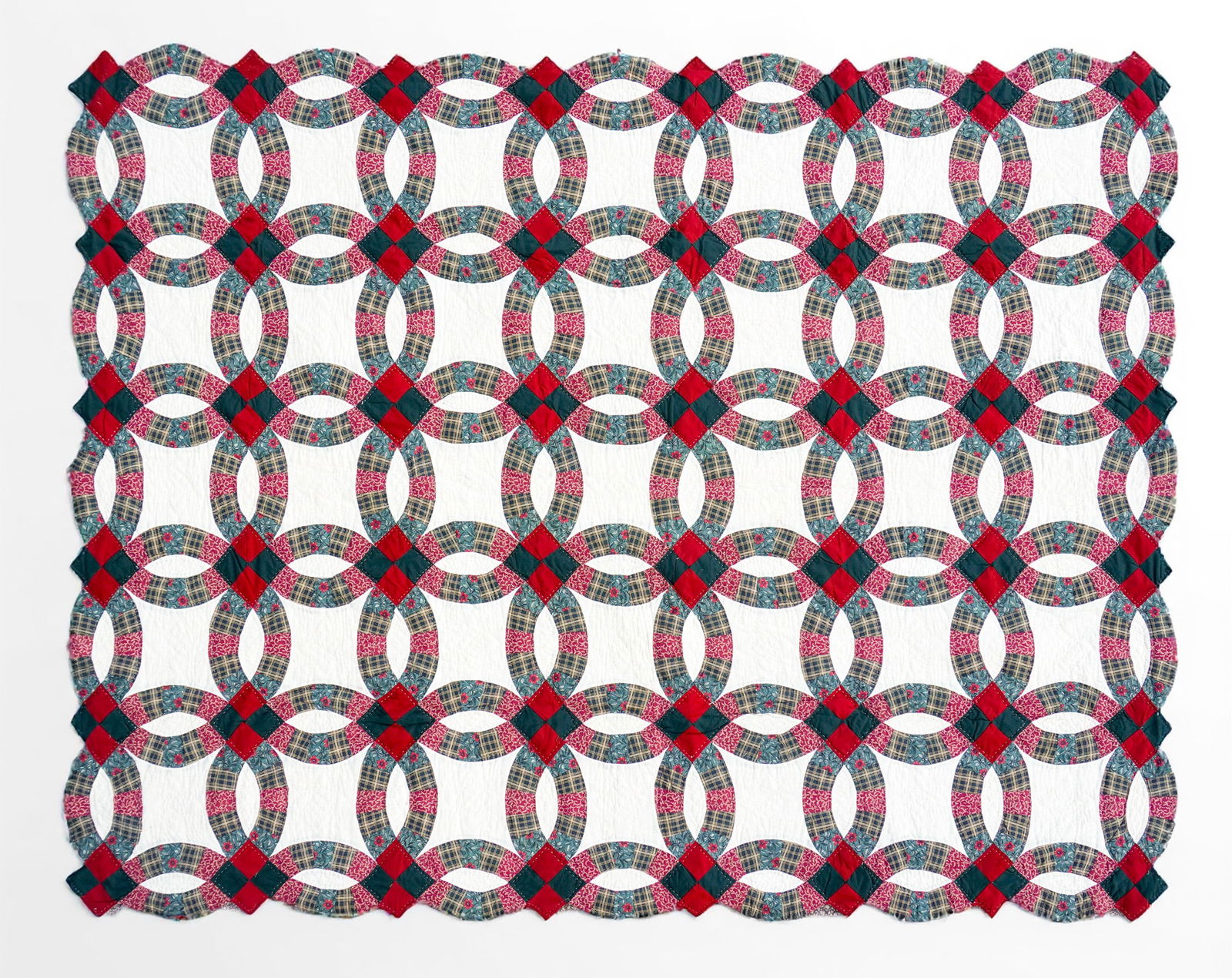 Mid-Century Double Wedding Ring Patchwork Quilt: This Double Wedding Ring quilt displays the beloved interlocking-ring pattern executed in teal, rose, red, and plaid cotton prints against a white ground. The quilt shows careful hand quilting through