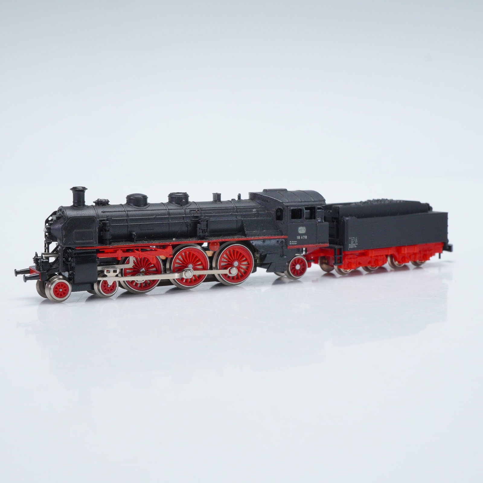 Marklin Mini Club Z Scale Steam Locomotive BR 38: Model no. 8893, modeled after the Deutsche Bundesbahn Class 38. It exhibits the quintessential characteristics of German steam engineering with its commanding black boiler and striking red running gea