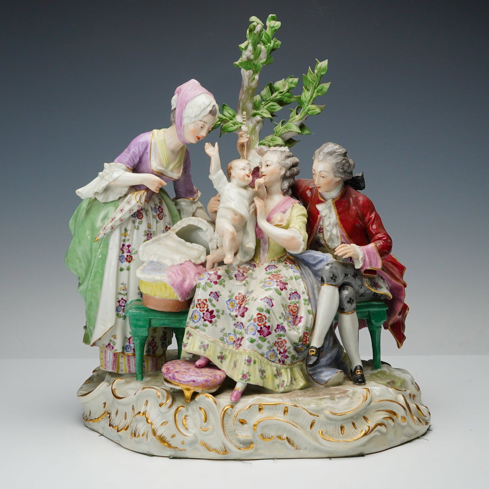 Samson Meissen Style Porcelain Family Sculpture: An 18th-century family scene, featuring a seated woman holding an infant while a man in period attire sits beside her, accompanied by a standing nursemaid leaning over a cradle; the composition includ