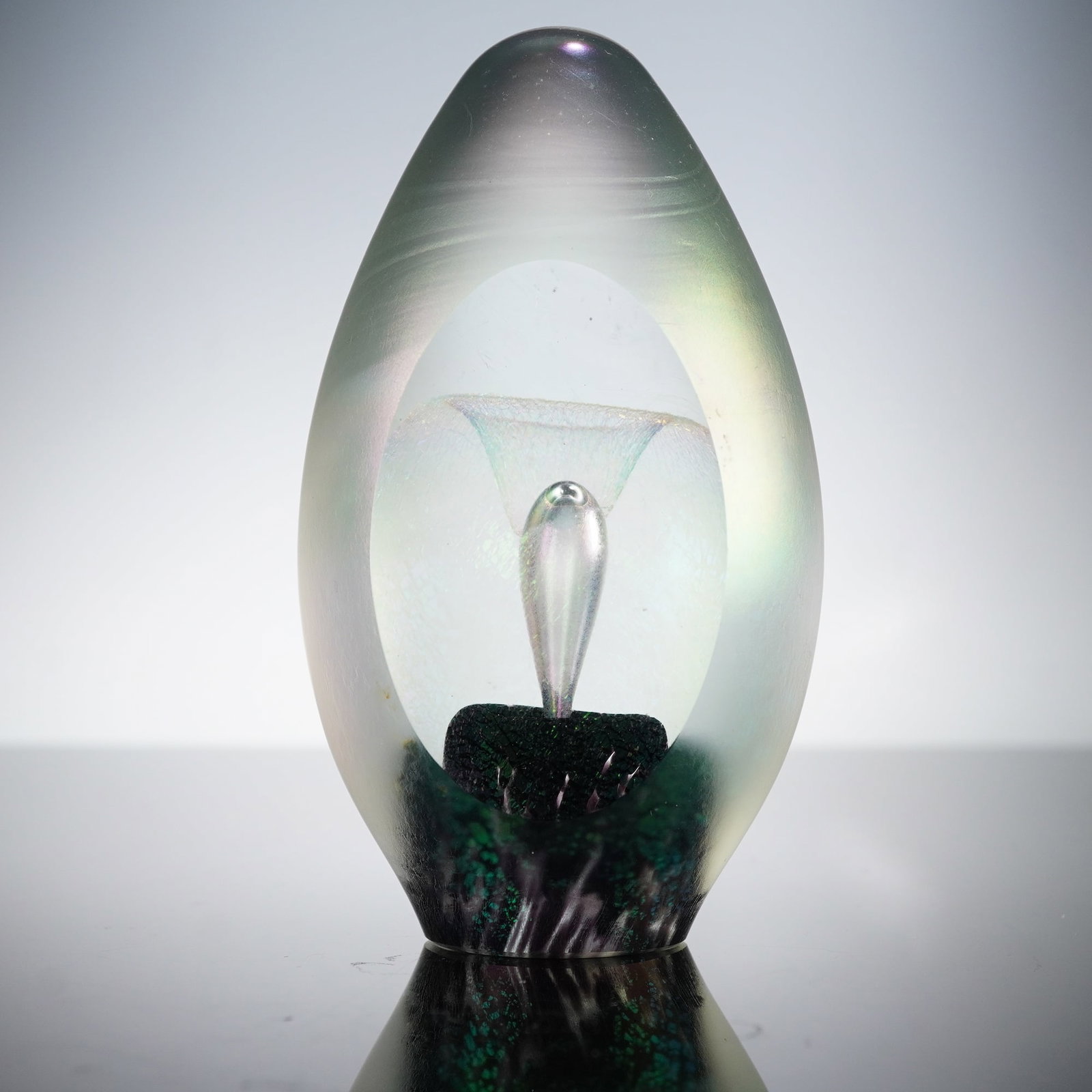 Robert Eickholt Studio Iridescent Frosted Art Glass Paperweight: A Robert Eickholt Studio iridescent frosted art glass paperweight. This ovoid art glass sculpture features a frosted, iridescent exterior encasing an abstract interior design. A clear, stylized form,