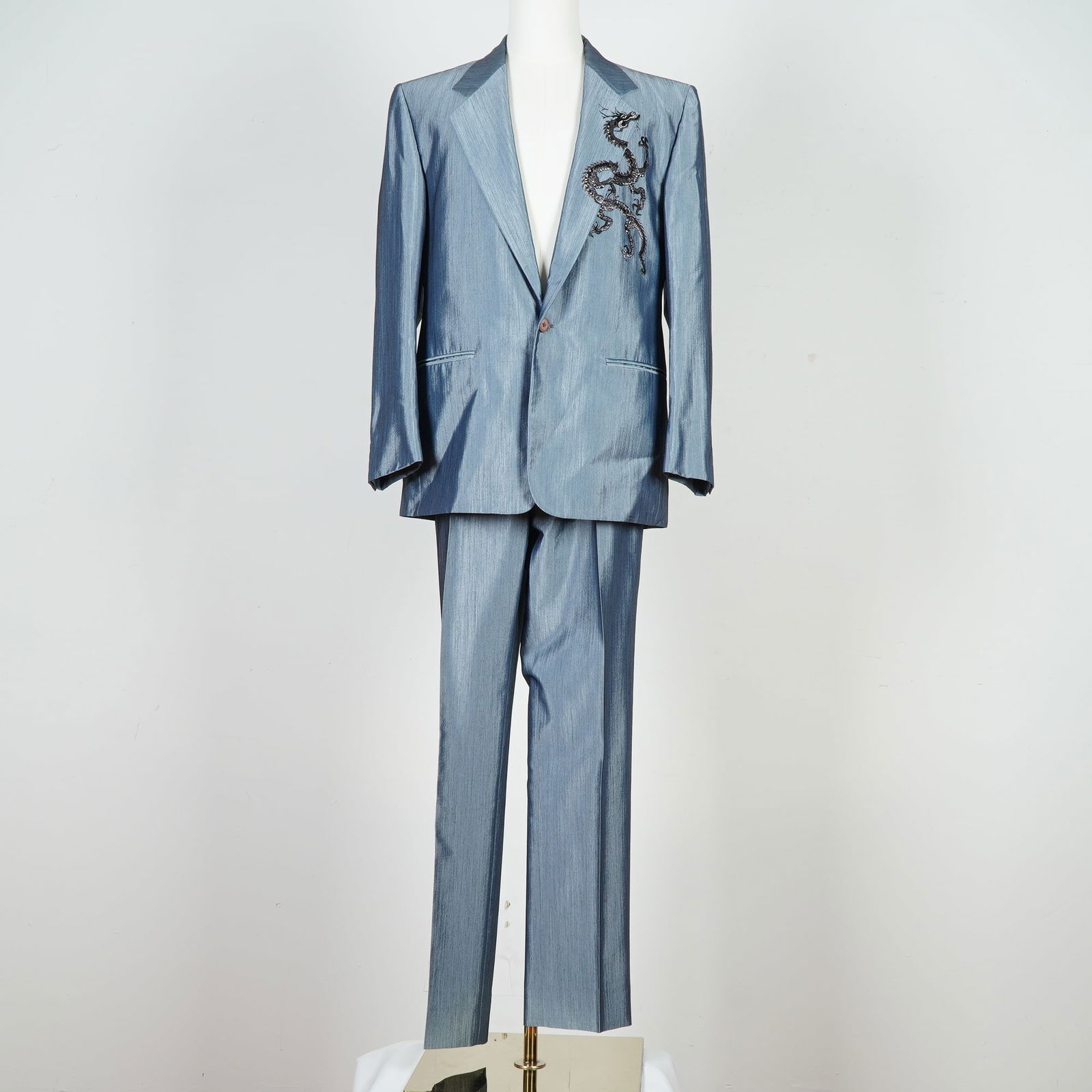 Gianni Versace Men's Suit, Light Blue Embroidered Dragon: This Gianni Versace two-piece suit is crafted from a light blue fabric with a subtle sheen. The single-breasted jacket features a peak lapel, a single button closure, and two front welt pockets. A det