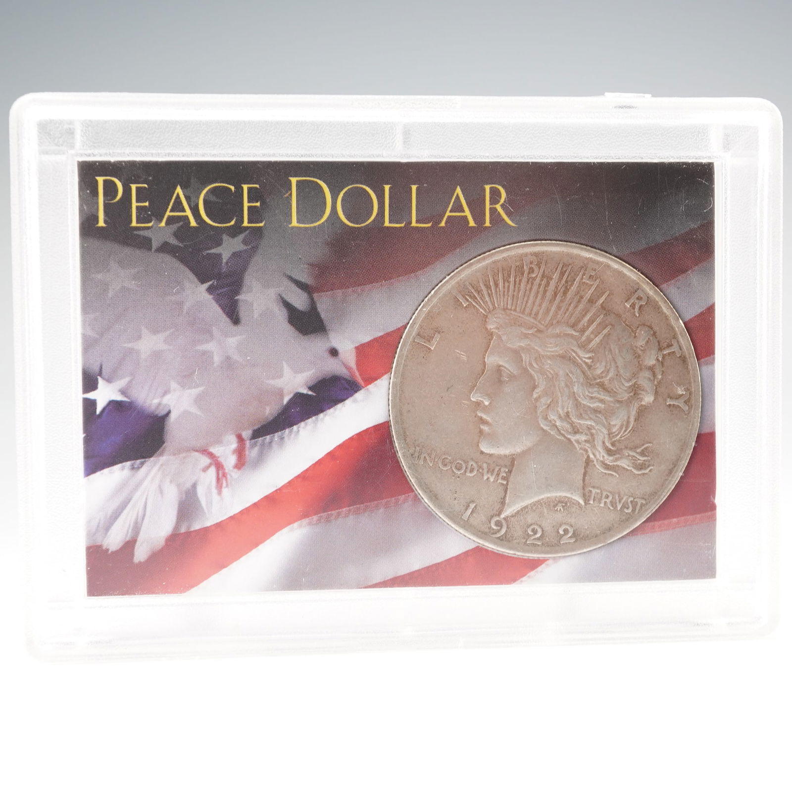 1922 Peace Silver Dollar: Encased in a display holder by Whitman Publishing, LLC. The obverse features the profile of Liberty wearing a radiant crown, with inscriptions LIBERTY, IN GOD WE TRVST, and the date 1922. The reverse