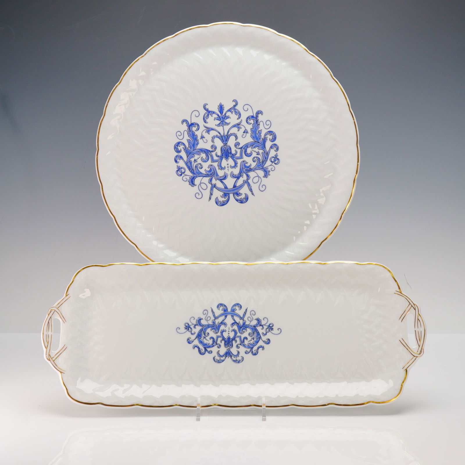 A Pair of Bernardaud Limoges 'Louis XIII' Porcelain Serving Wares: A pair of Bernardaud Limoges 'Louis XIII' porcelain serving pieces, comprising one large round platter and one smaller rectangular tray with handles. Each piece features a white porcelain body with a