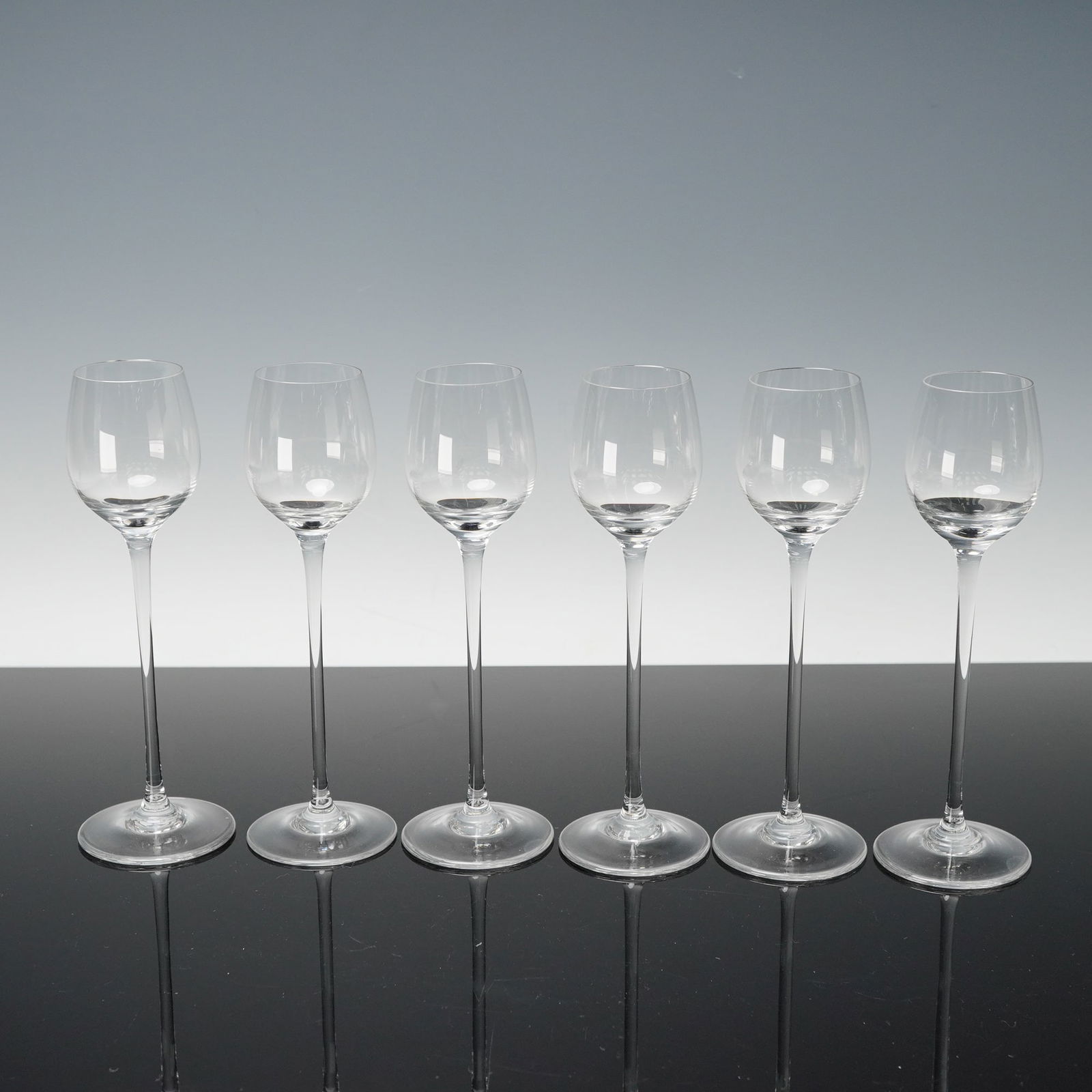 6pc Riedel Crystal Cordial Wine Glasses: A set of six Riedel crystal cordial wine glasses, each crafted in clear fine crystal with tall slender stems, rounded bowls, and polished circular feet, all bearing the etched Riedel signature to the