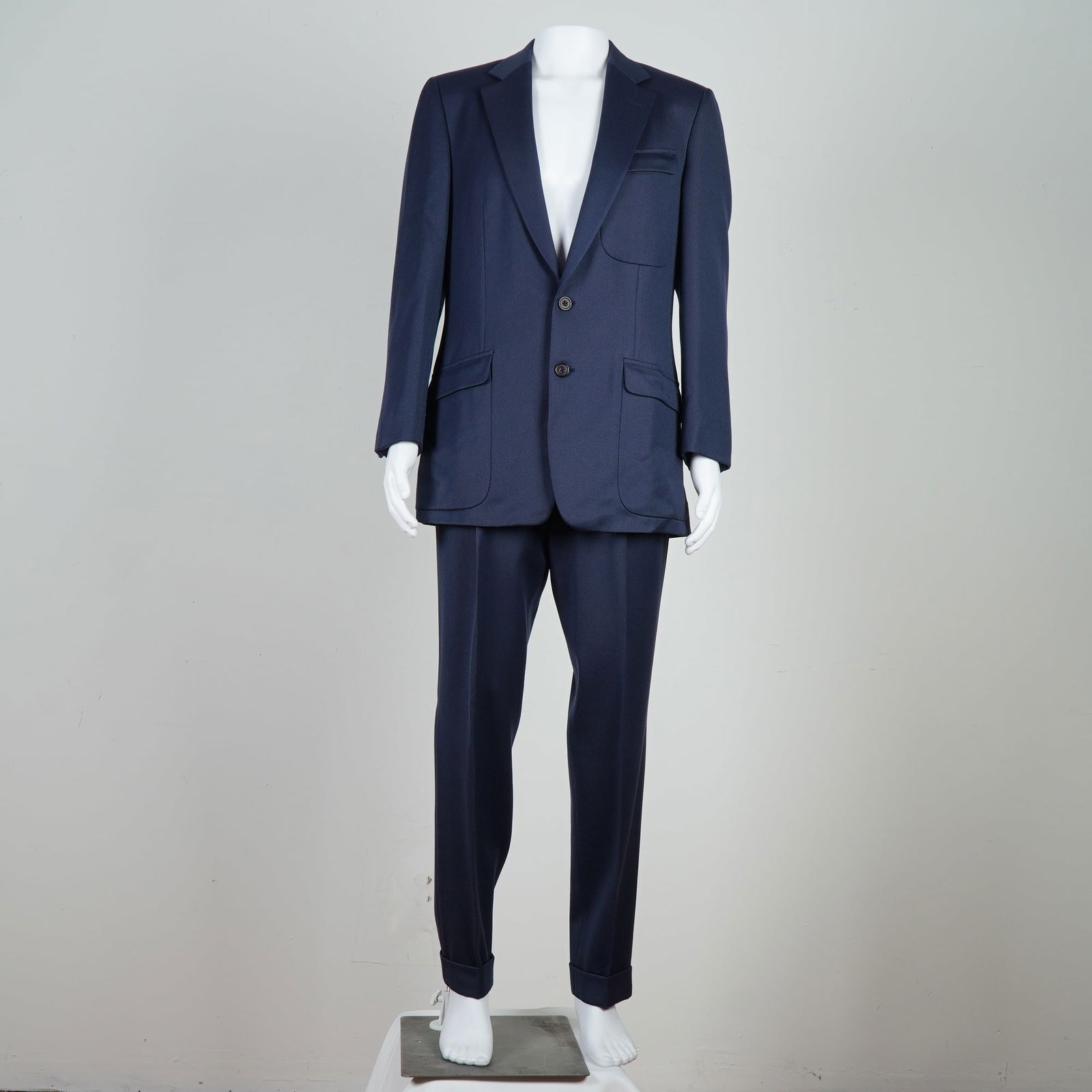 Gianni Versace Men's Wool Suit, Navy: A finely tailored two-piece suit by Gianni Versace, crafted in navy wool. The jacket features a structured silhouette with a notched lapel, two-button front closure, and dual flap pockets with a welte
