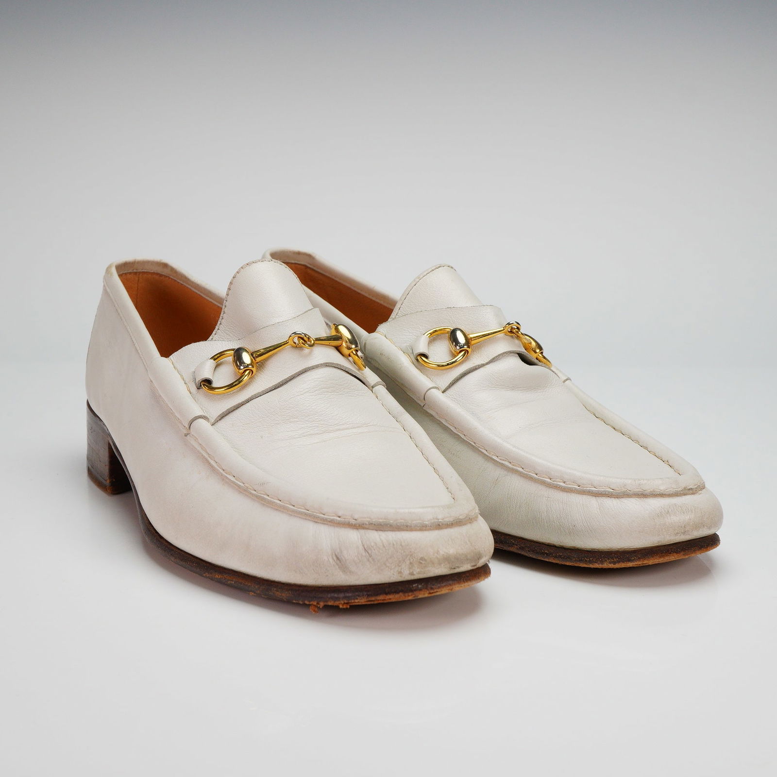 Pair of Gucci Men's Leather Horsebit White Loafers: Pair of Gucci men's loafers crafted in white leather, featuring the iconic gold-tone horsebit detail. Marked Gucci Made in Italy to interior, sole, and underside, size 43.5. Included with shoe inserts