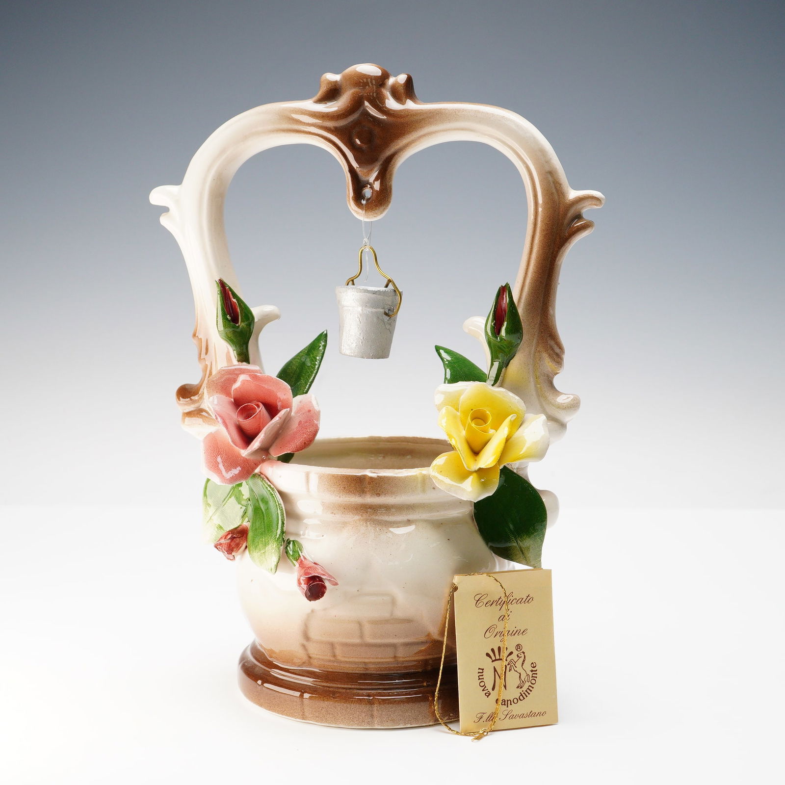 Nuova Capodimonte Italian Porcelain Wishing Well: Charming Nuova Capodimonte porcelain wishing well sculpture by F.lli Savastano, richly detailed with hand-modeled roses, leaves, and a suspended porcelain bucket. The piece is finished in warm cream a