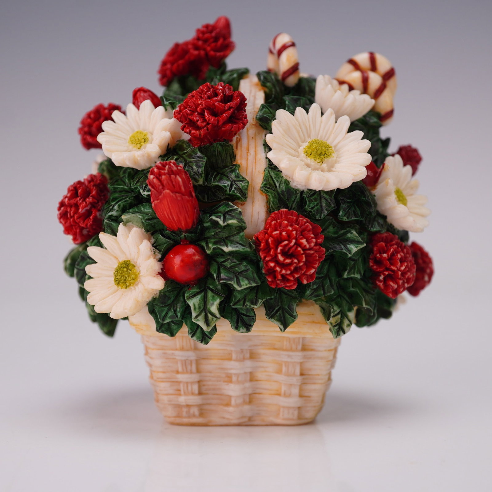 Harmony Ball Covered Box Figurine, First Christmas: Part of the Lord Byron's Harmony Garden Bouquets collection. The exterior is modeled as a woven basket filled with red and white flowers and decorated with candy canes. The interior reveals a sculpted
