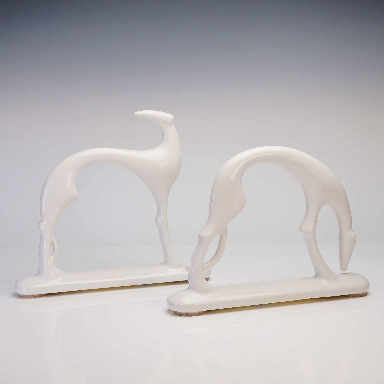 A Pair of Haeger Mid-Century Modern White Ceramic Greyhound Sculptures: A pair of Haeger greyhound figurines, executed in a Mid-Century Modern or streamline aesthetic. These sculptures, commonly identified as Whippet or Greyhound dogs, are rendered in highly glossy white