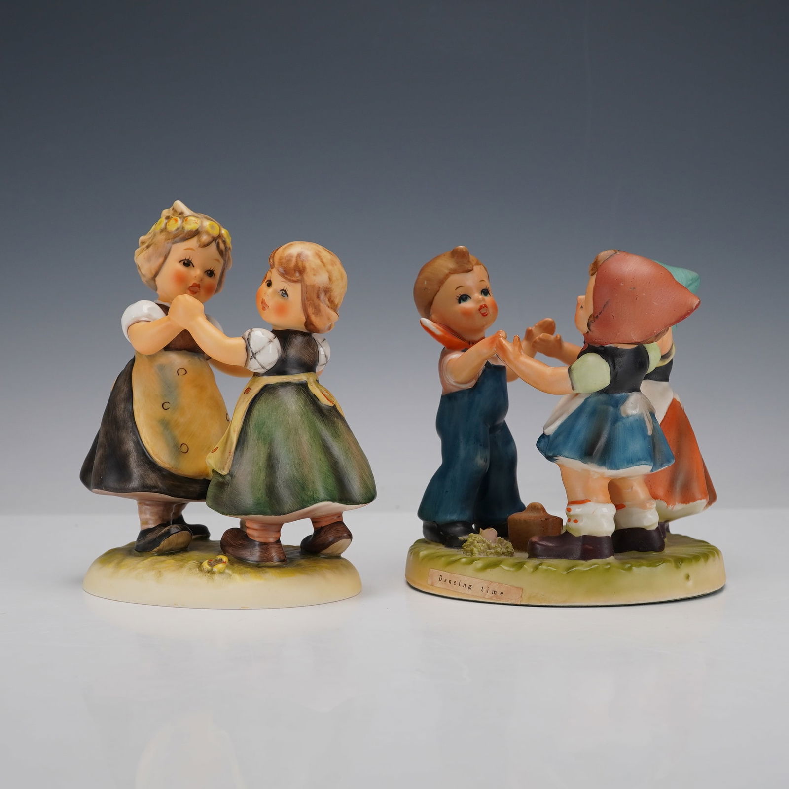 2pc Goebel Hummel and Artnart Porcelain Children Figurines: Hand painted figures including Goebel Hummel Caribbean Collection Spring Dance with two girls holding hands in traditional dress and Dancing Time with a boy and two girls in a circle formation, design