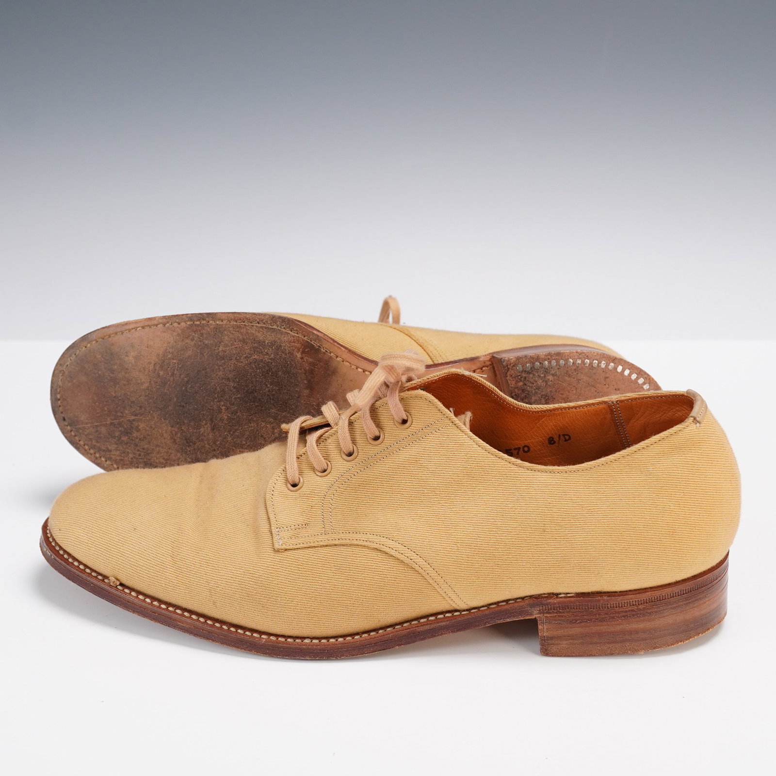 Neiman Marcus English-Made Canvas Oxford Shoes: A refined pair of men's oxford shoes retailed by Neiman Marcus, crafted in England with a tan canvas upper and leather soles. These classic lace-up shoes feature stitched leather detailing, a stacked 