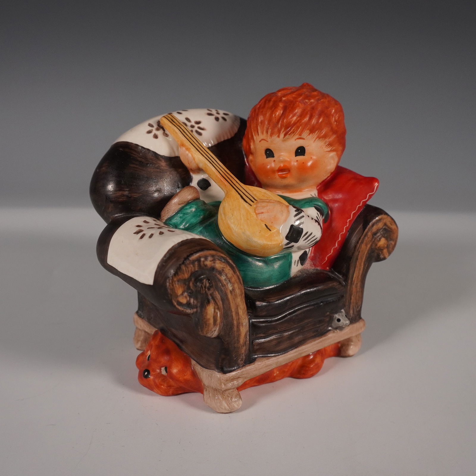 Goebel Hummel Figurine, Byj Off Key: Charming Goebel Hummel figurine, model Byj 22, titled Off Key, crafted in West Germany and dated 1958. This hand-painted ceramic figurine features a young child with vibrant red hair seated in a cozy