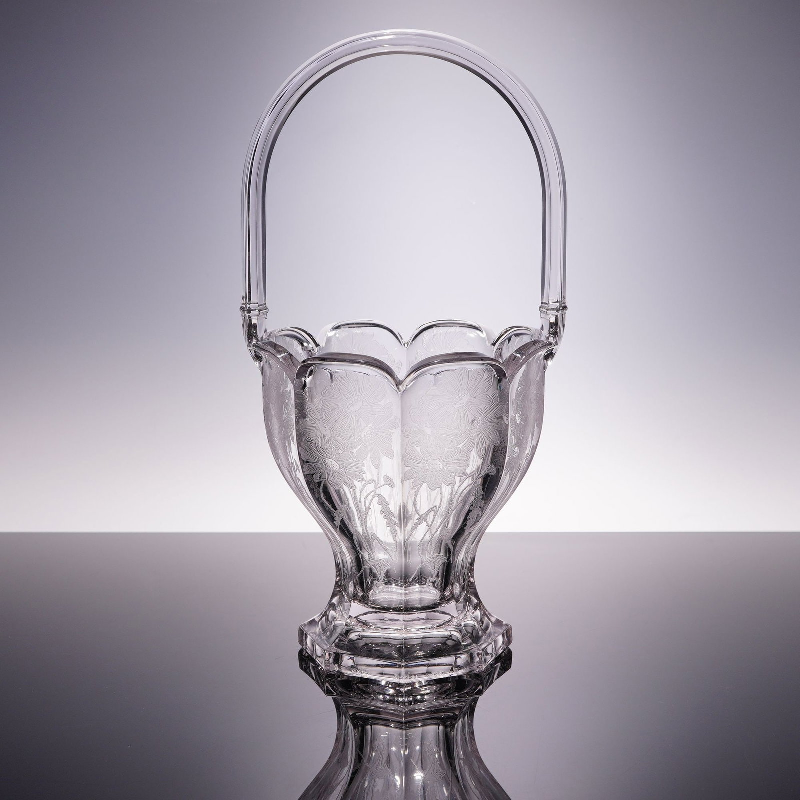 Heisey Etched Glass Basket: Exquisite Heisey crystal glass basket featuring an elegant floral etched design across a paneled body with scalloped rim. The basket handle arches gracefully above the flared form, meeting at reinforc