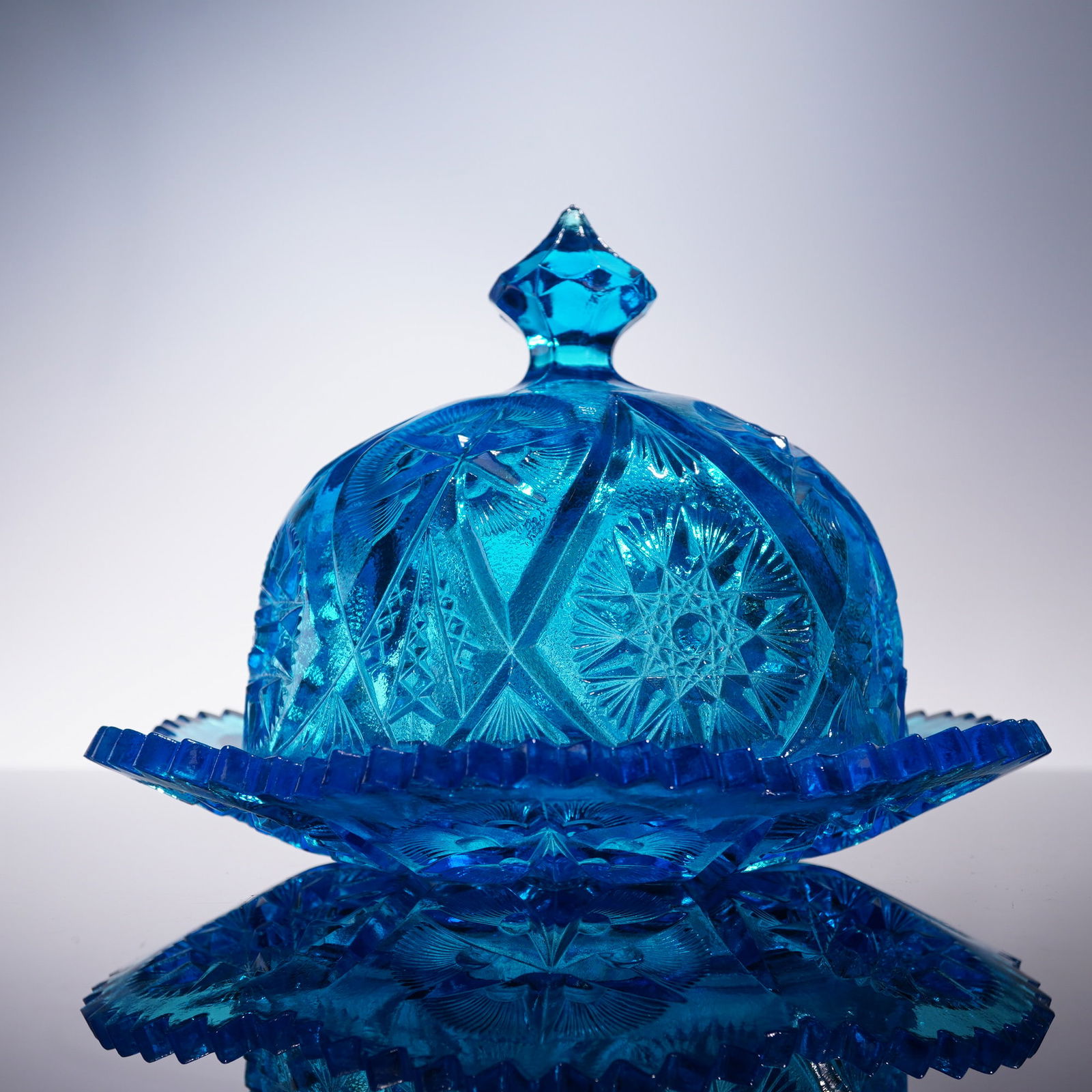 Kemple Yutec Star Blue Covered Dish Pressed Glass: This vintage Kemple Yutec Star covered dish is crafted in pressed glass with a vibrant blue hue and a detailed star and fan pattern associated with the Yutec line. Its bold geometric motif reflects th