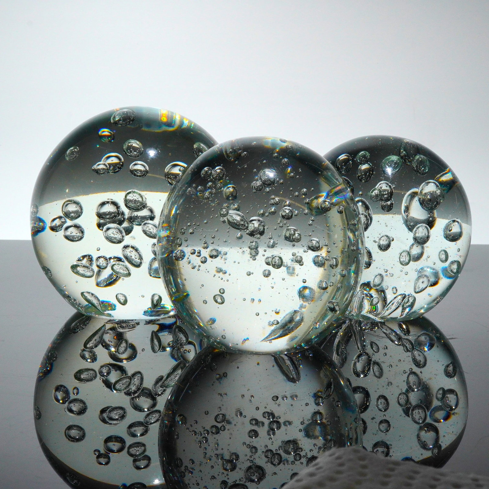 Three Clear Glass Spheres with Controlled Bubble Inclusions: A trio of clear glass spheres, commonly marketed as decorative objects. These objects are crafted using transparent glass and feature dense, multi-sized controlled air bubble inclusions distributed th
