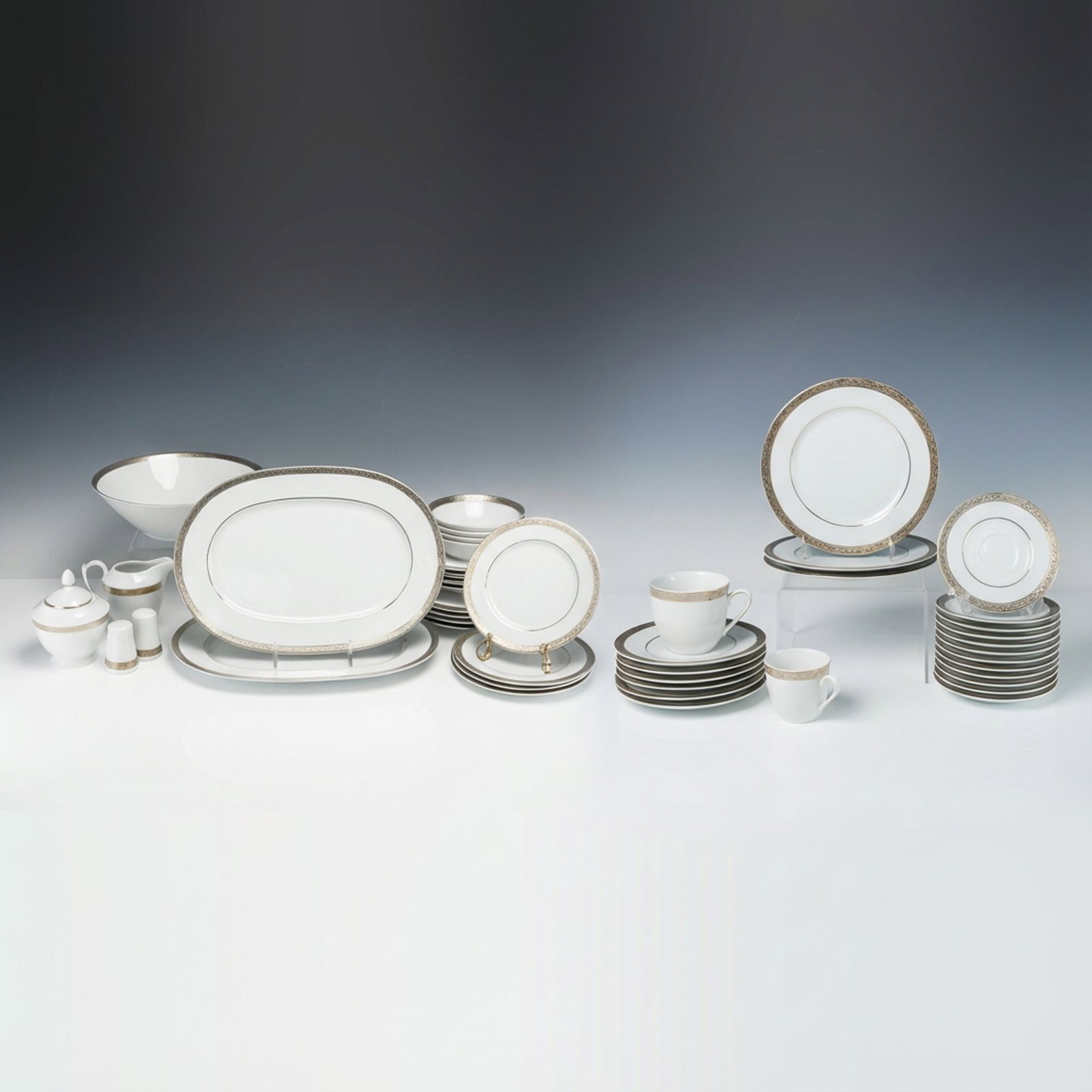 46 Falken-Porzellan Bavaria Gilt-Bordered Service Pieces: A 46-piece collection of Falken-Porzellan Bavaria service ware crafted from white porcelain. The set features a wide metallic border executed in a repeating geometric and stylized foliate pattern, acc