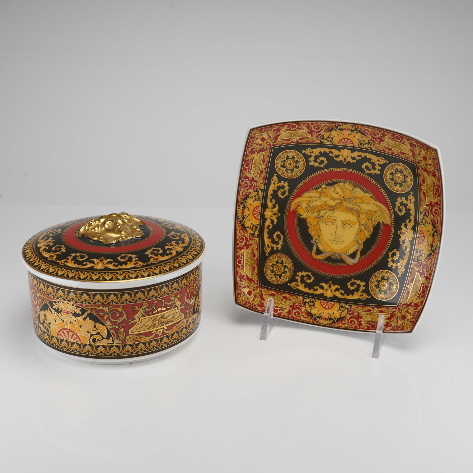 A Pair of Rosenthal Versace Medusa Porcelain Accessories: A two-piece collection of Rosenthal Versace Medusa porcelain accessories, executed in a highly ornamental Neo-Classical/Baroque style. The 2pc lot comprises one circular lidded box and one slightly ro