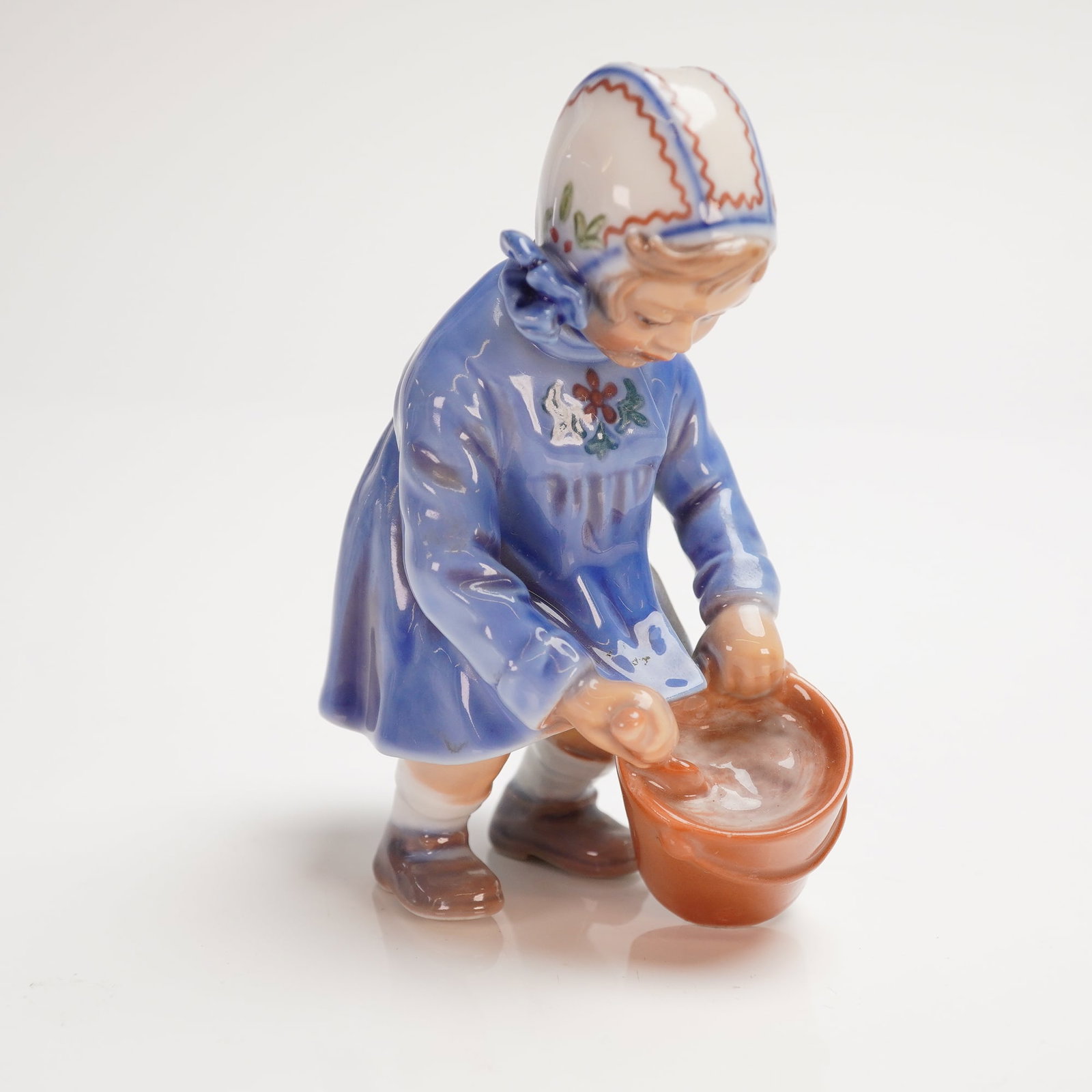 Dahl Jensen Copenhagen Porcelain Figurine Girl with Pail No. 1151: A single glazed porcelain figurine attributed to Dahl Jensen (DJ), Copenhagen, model number 1151, titled Girl with Pail or Girl with Bucket. The DJ Figurine depicts a young girl dressed in a flowing b