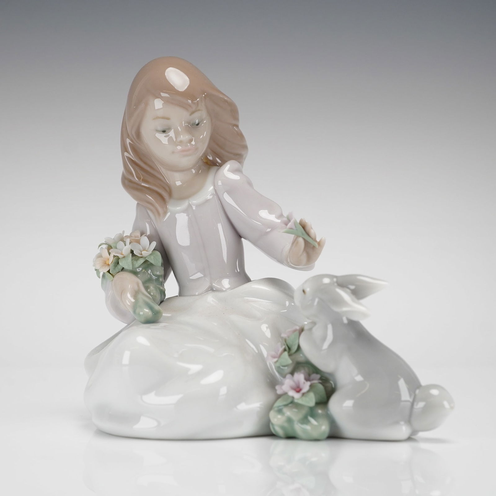 Lladro Forestland Encounter Figurine Model 6931: A single glazed porcelain figurine, Lladros "Forestland Encounter," model number 01006931. The piece depicts a seated young girl, rendered in soft pastel tones, wearing a pale lavender top and a white