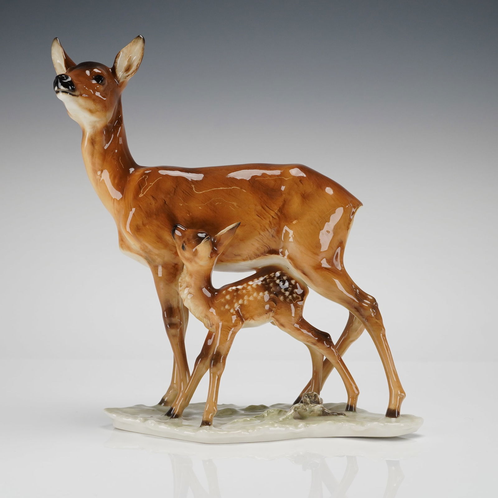 Hutschenreuther Selb Porcelain Fawn and Doe Figurine: A figural sculptural group crafted from glazed porcelain by Hutschenreuther Selb, Germany. The piece depicts a naturalistic wildlife scene featuring a doe standing with her head raised, accompanied by