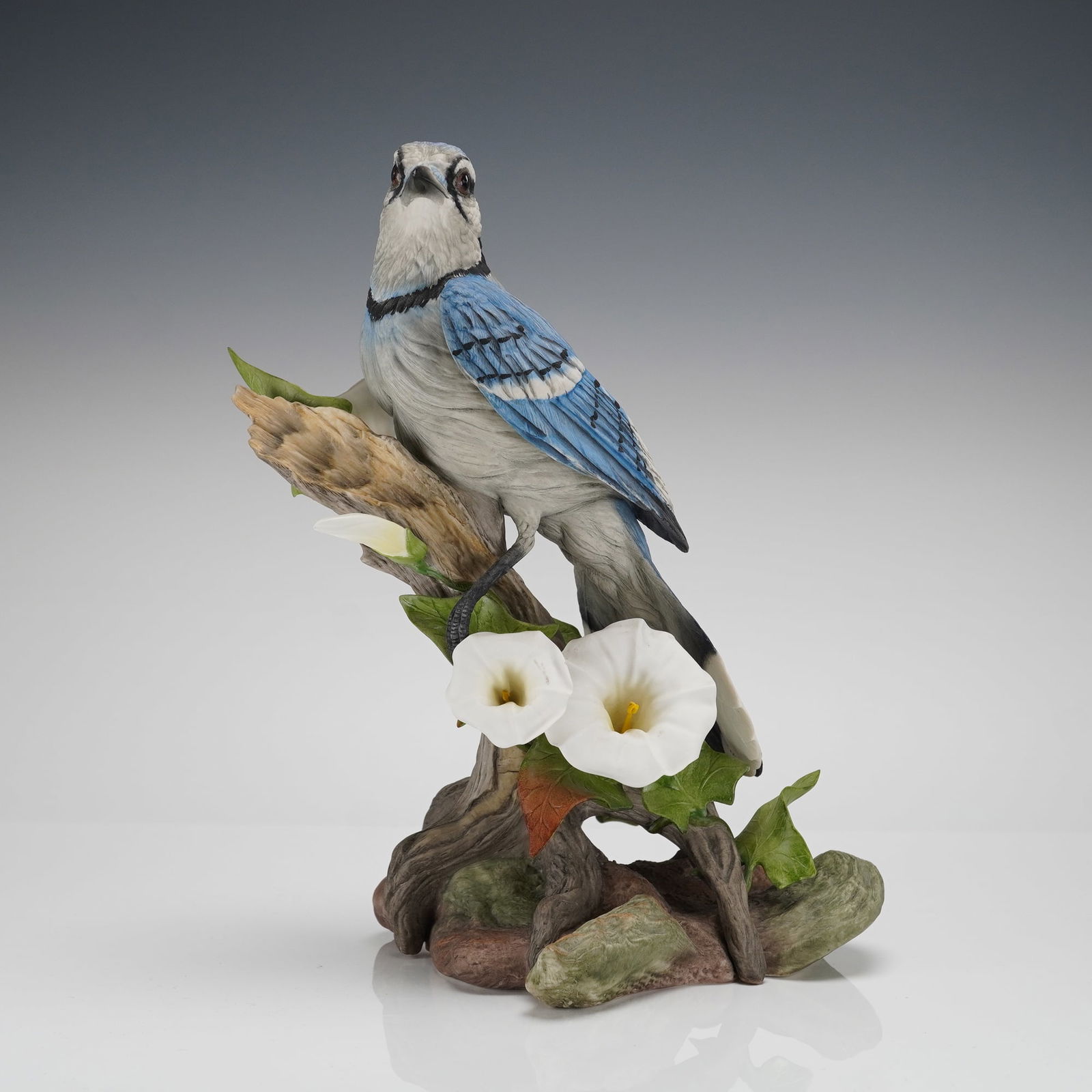 Edward Marshall Boehm Limited Edition Blue Jay Porcelain Figurine: A single Boehm Blue Jay with flowers matte figurine, executed in hand-painted porcelain. This limited edition figurine depicts a realistic Blue Jay perched on a naturalistic base composed of a stylize