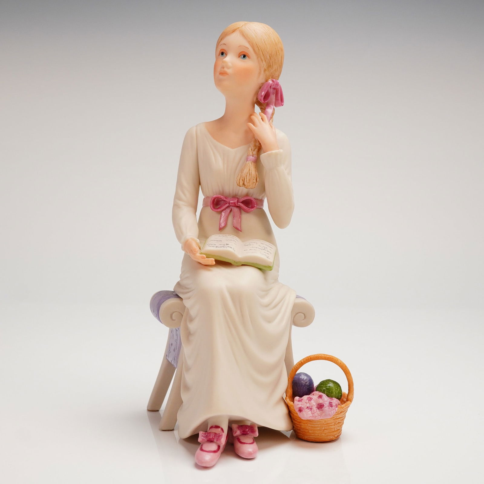Cybis Matte Porcelain Figurine, "Wendy": A single matte girl figurine, attributed to Cybis, depicting a young girl likely representing the "Wendy" character, executed in matte (bisque) porcelain. The figure is shown seated on a lavender-cush