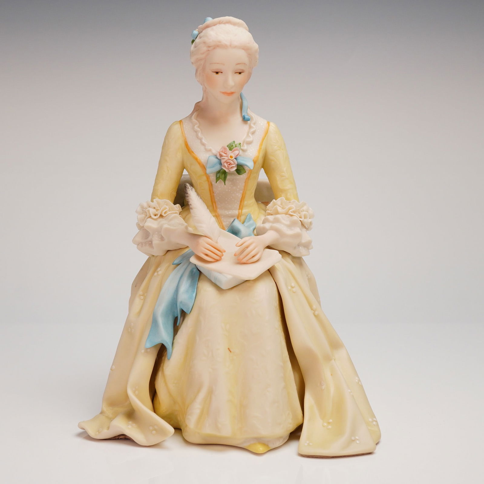 Cybis Porcelain Figurine of a Seated Rococo Woman Model 327: A single hand-painted porcelain figural sculpture by Cybis, depicting a seated woman in 18th-century Rococo-style attire. The figure is crafted with a matte finish. The woman wears a pale yellow gown