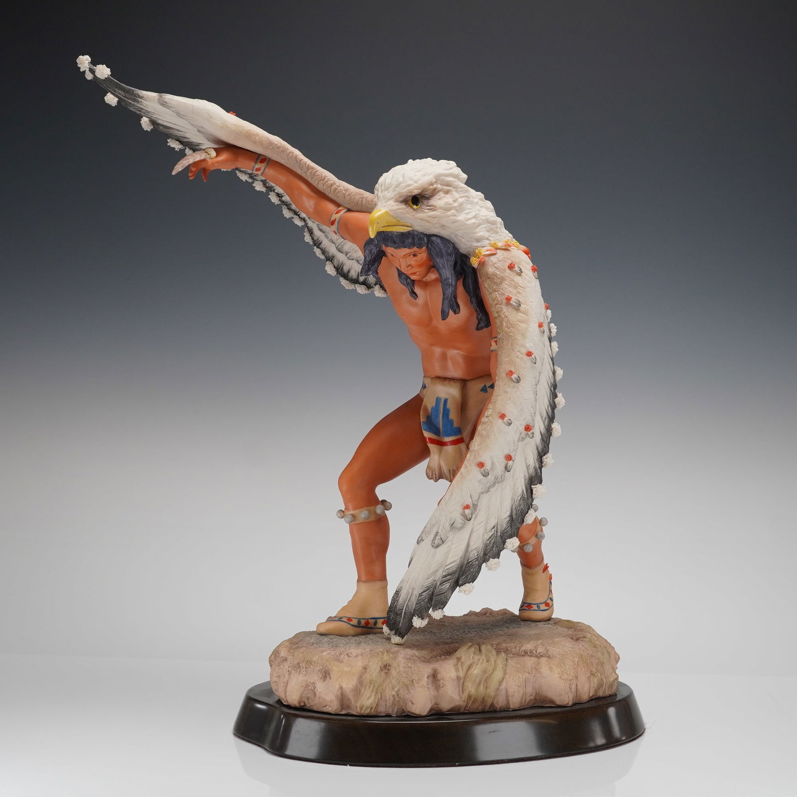 Cybis North American Indians Eagle Dancer Sculpture, Dated 1984: A single polychrome figural sculpture, likely constructed from painted resin or polystone, depicting a Native American male dancer performing the Eagle Dance. The figure is shown in a dynamic, leaning