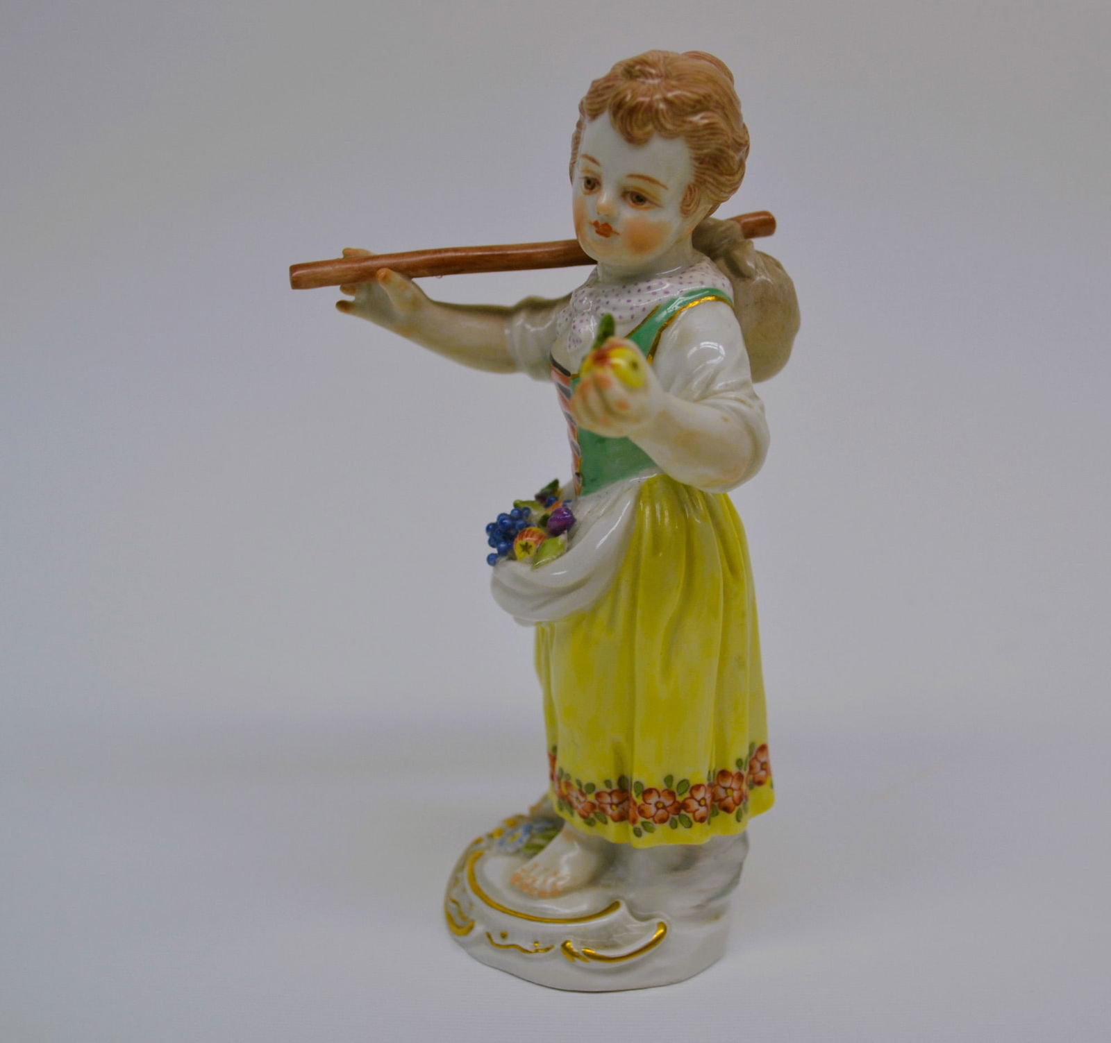 Antique Meissen Porcelain Young Girl Gathering Fruit Figurine: Meissen Porcelain Ware, Hand made and hand painted, Porcelain Decorated, with overglaze. Porcelain Figurine of a Young Girl Gardener Child with staff and fruit. Standing, barefooted with high hair in