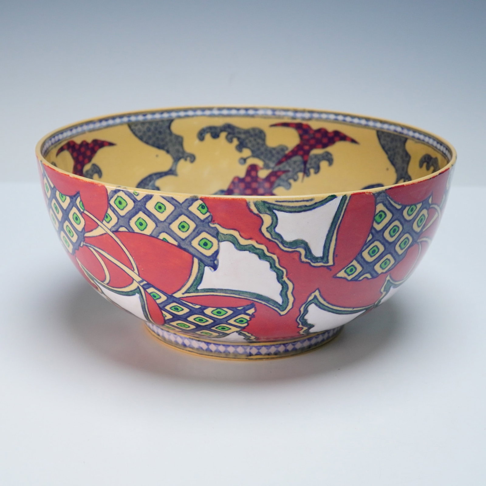 Wedgwood Art Deco Earthenware Bowl with Asian-Inspired Motifs: A vibrant Art Deco earthenware bowl by Wedgwood, made in England, circa 1920s-1930s, decorated with a fusion of geometric patterning and Asian-inspired imagery. The interior features wave and cloud fo